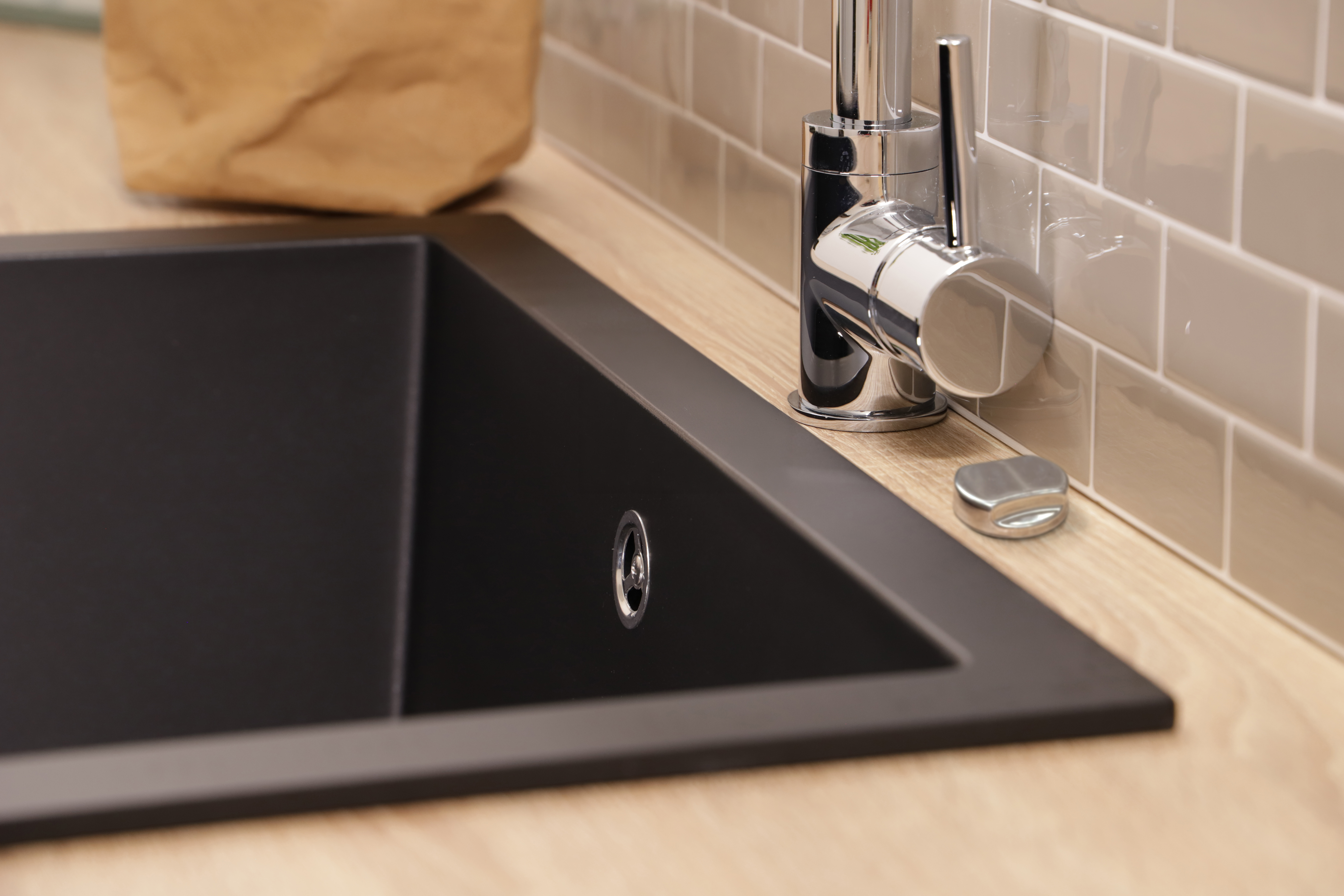 Eine schwarze Spüle neben einem Wasserhahn und einer braunen Papiertüte.