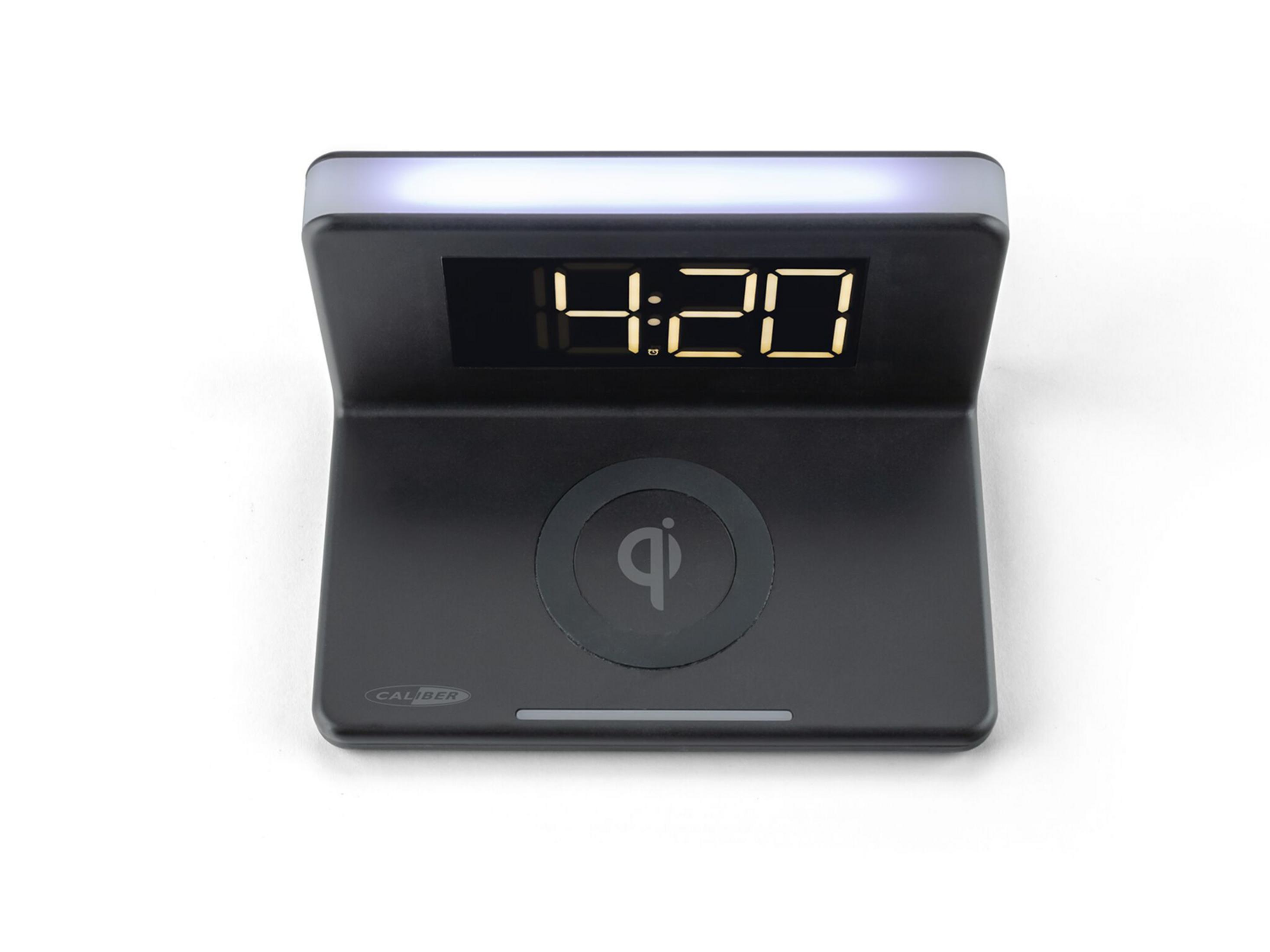 Black digital alarm clock with Qi charging pad and illuminated display.