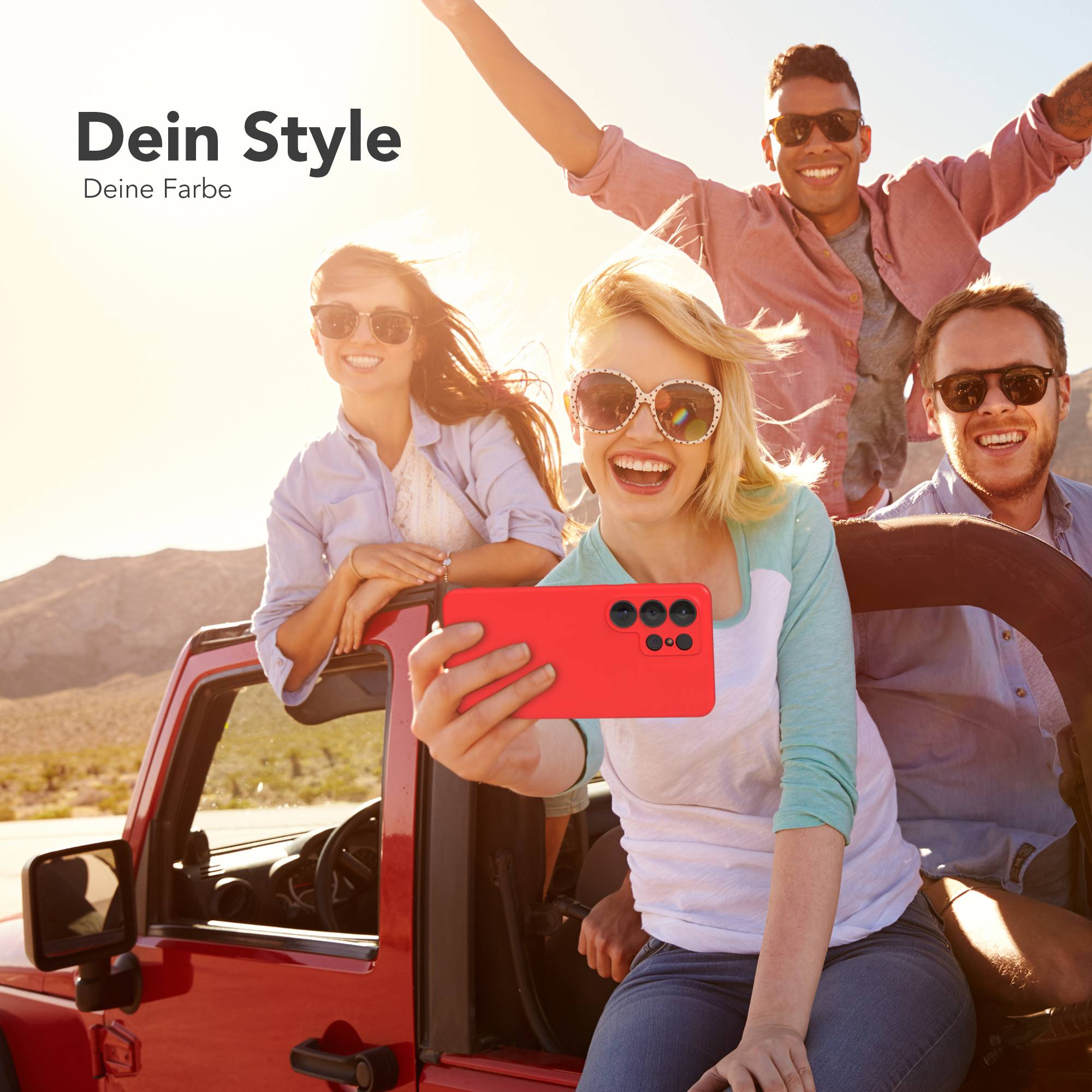 Vier junge Leute in einem roten Jeep machen ein Selfie mit einem roten Handy.