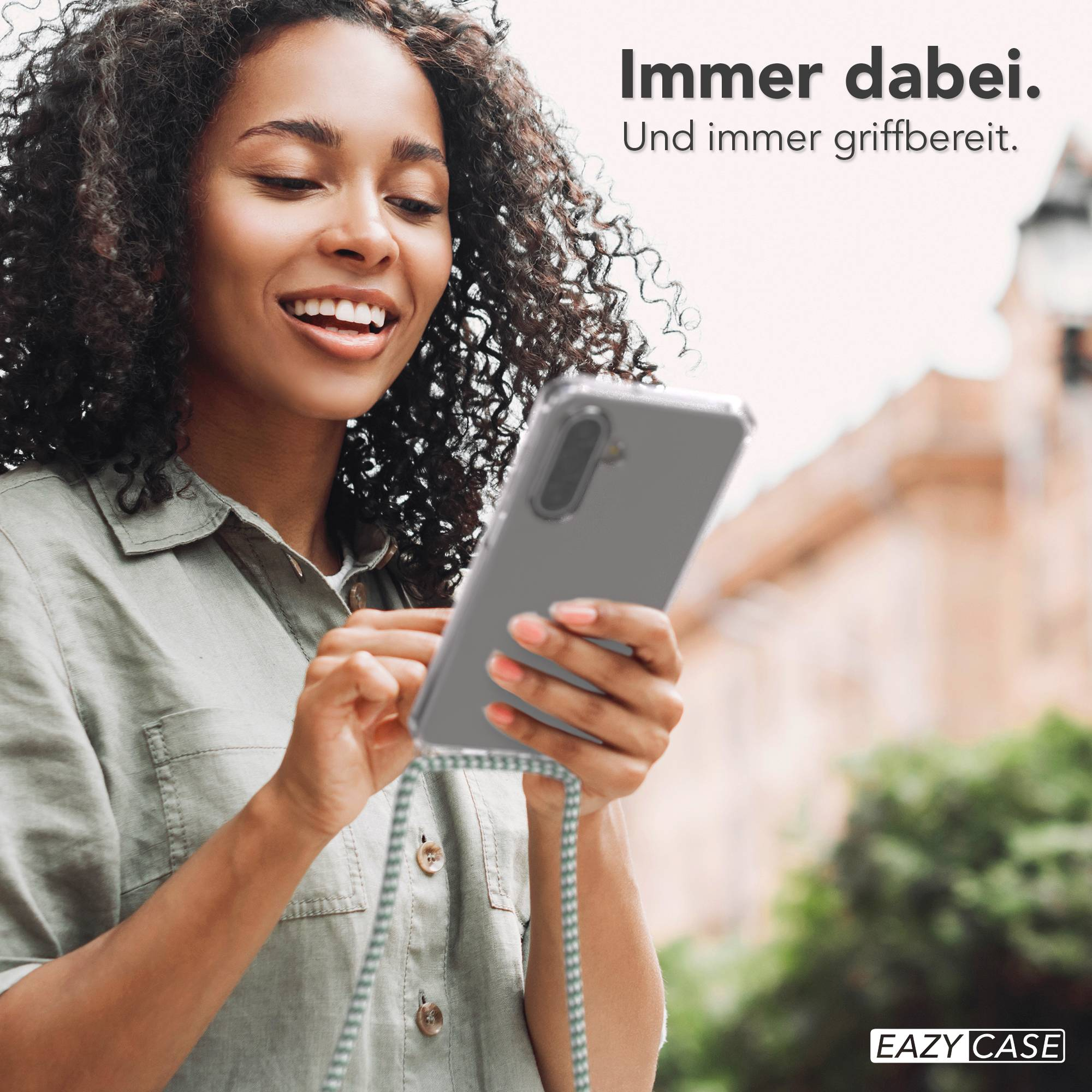 Eine Frau mit lockigen Haaren hält ein Smartphone in einer Hülle mit Band.