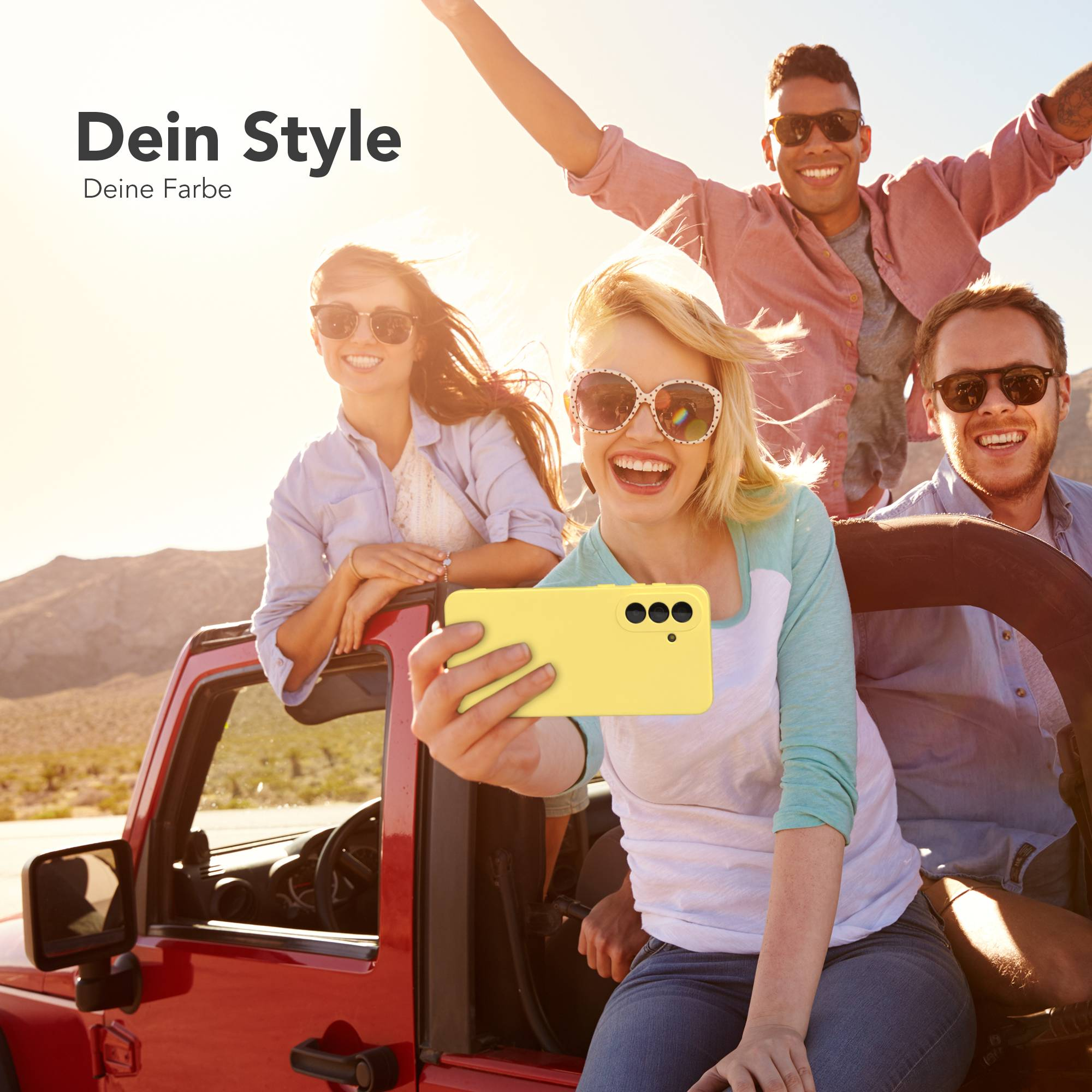 Freunde machen Selfie mit gelbem Handy vor rotem Jeep in sonniger Wüste.