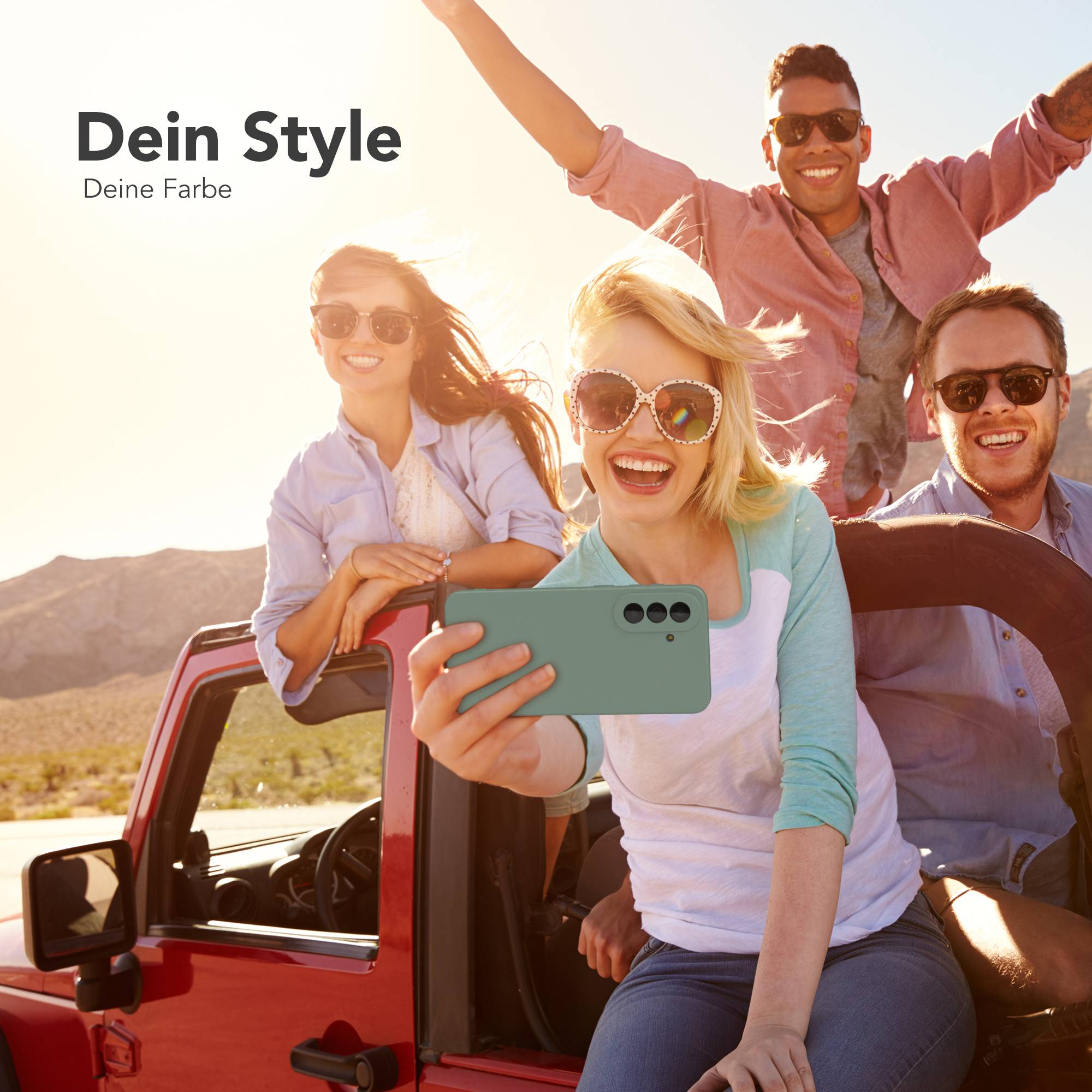 Freunde machen Selfie in einem roten Jeep mit einem Handy, Wüste im Hintergrund.