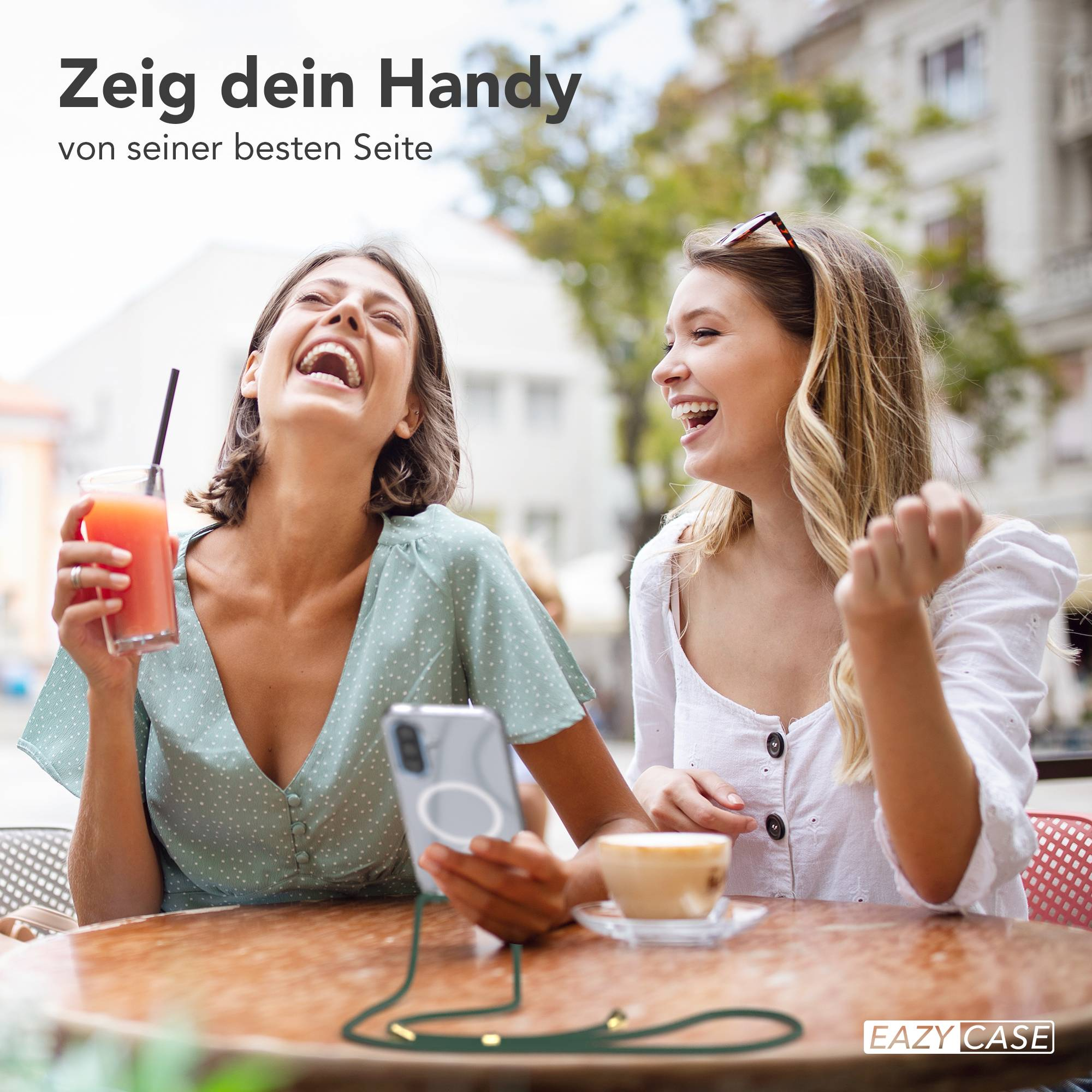 Zwei Frauen lachen, eine hält ein Getränk, die andere eine Kaffeetasse.