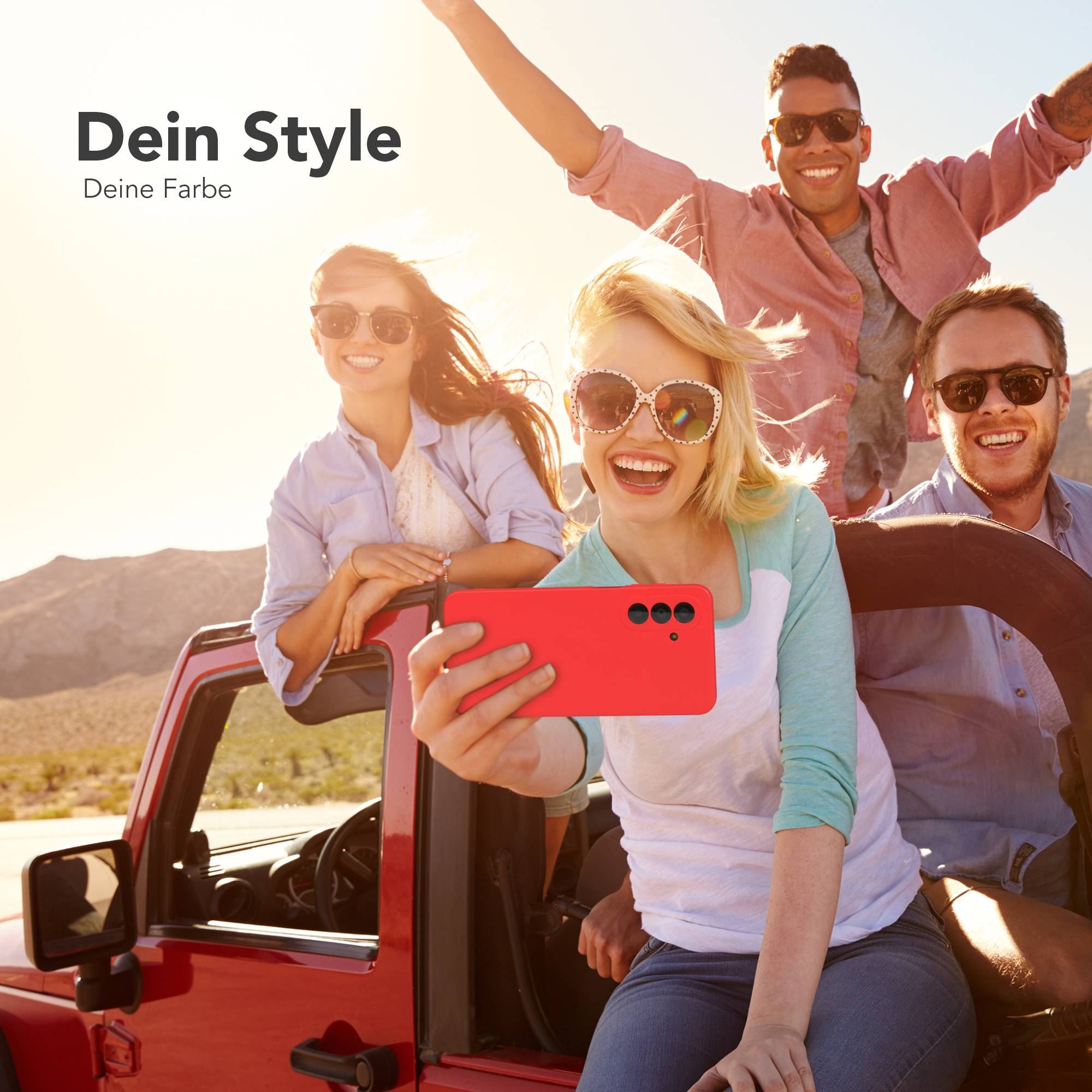 Vier Freunde im roten Jeep, eine Frau macht ein Selfie mit einem roten Handy.