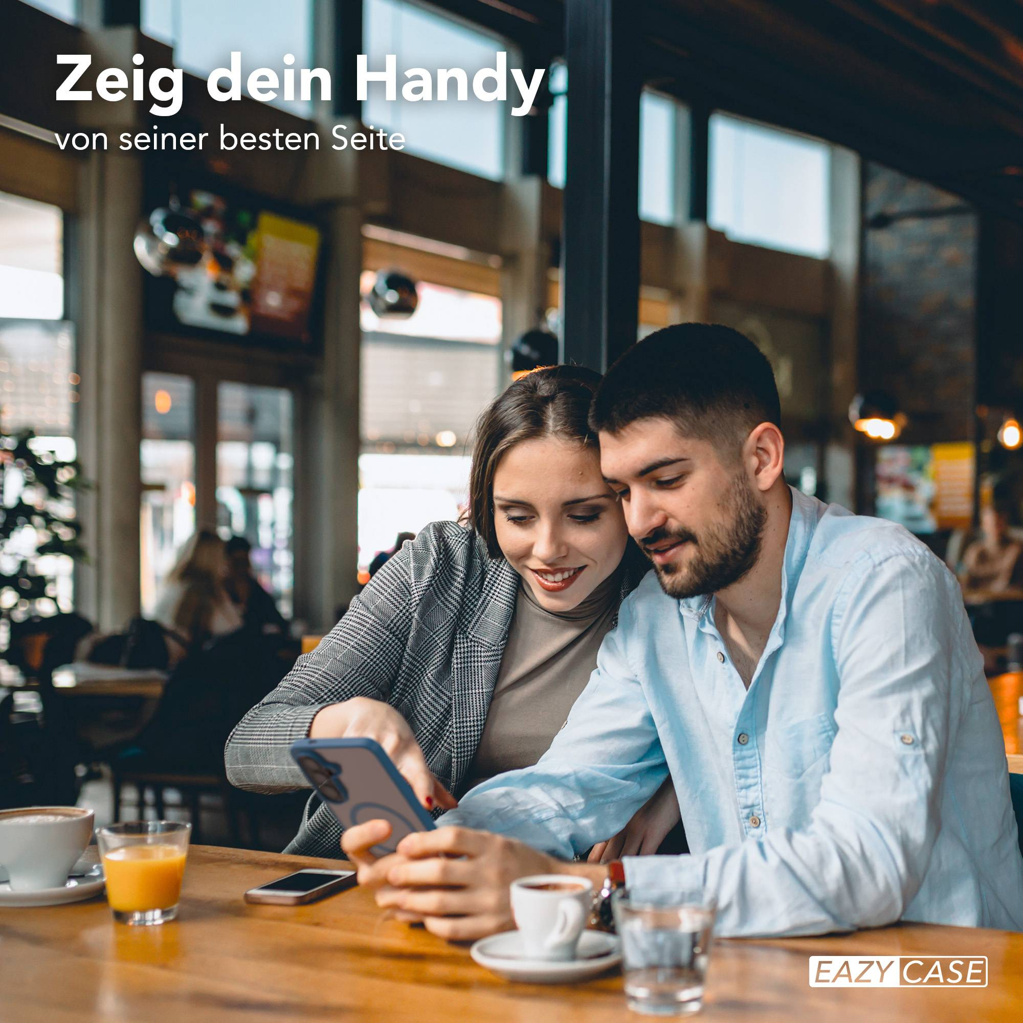 Ein Mann und eine Frau sitzen an einem Tisch und schauen auf ein Handy.