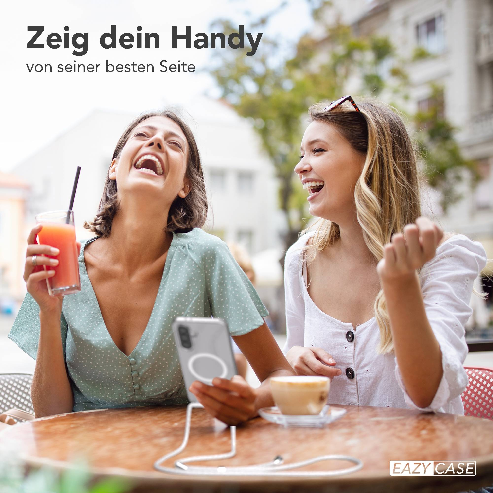 Zwei lachende Frauen sitzen an einem Tisch mit Getränken und Kaffee.