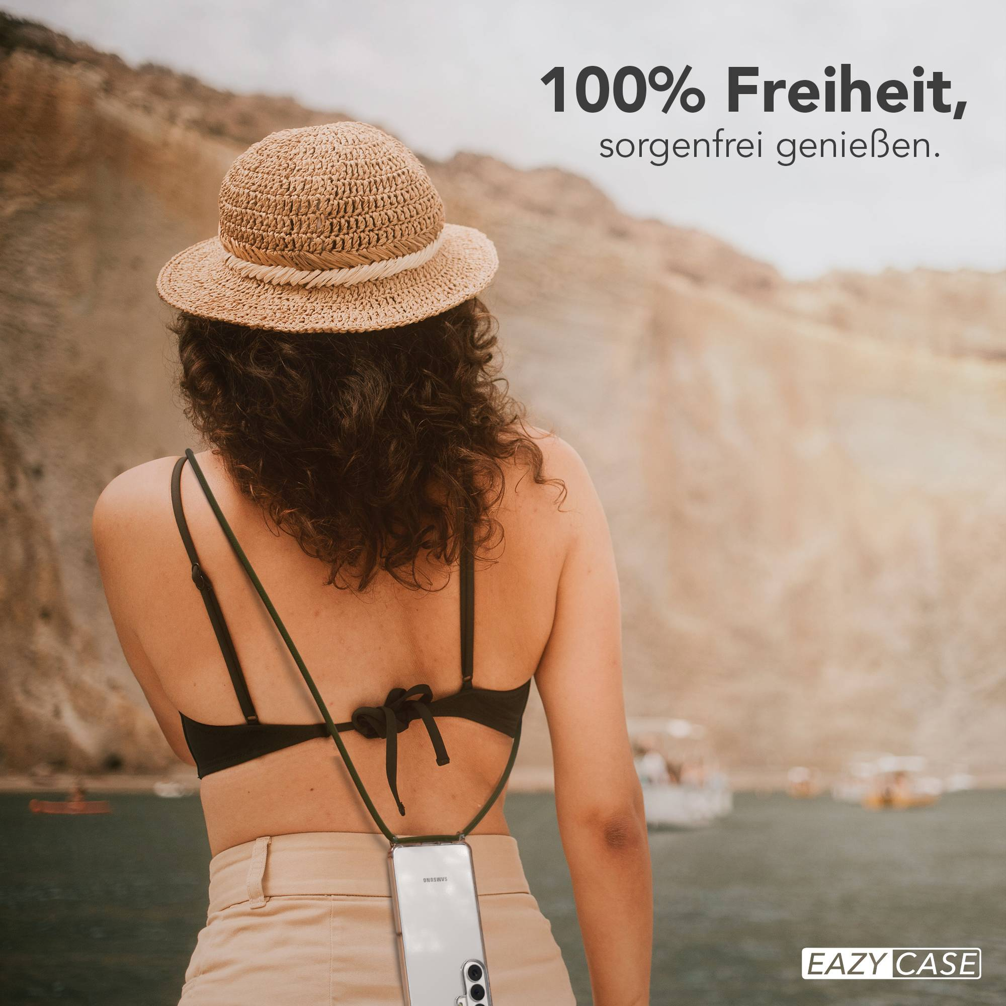 Frau mit Strohhut, schwarzem Bikini und beiger Hose am Wasser.