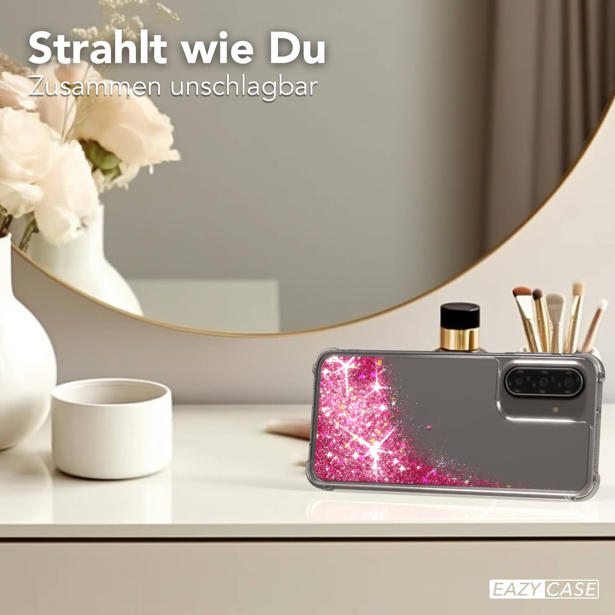 Graue Handyhülle mit glitzerndem pinkem Sternenmuster, auf einem Tisch.