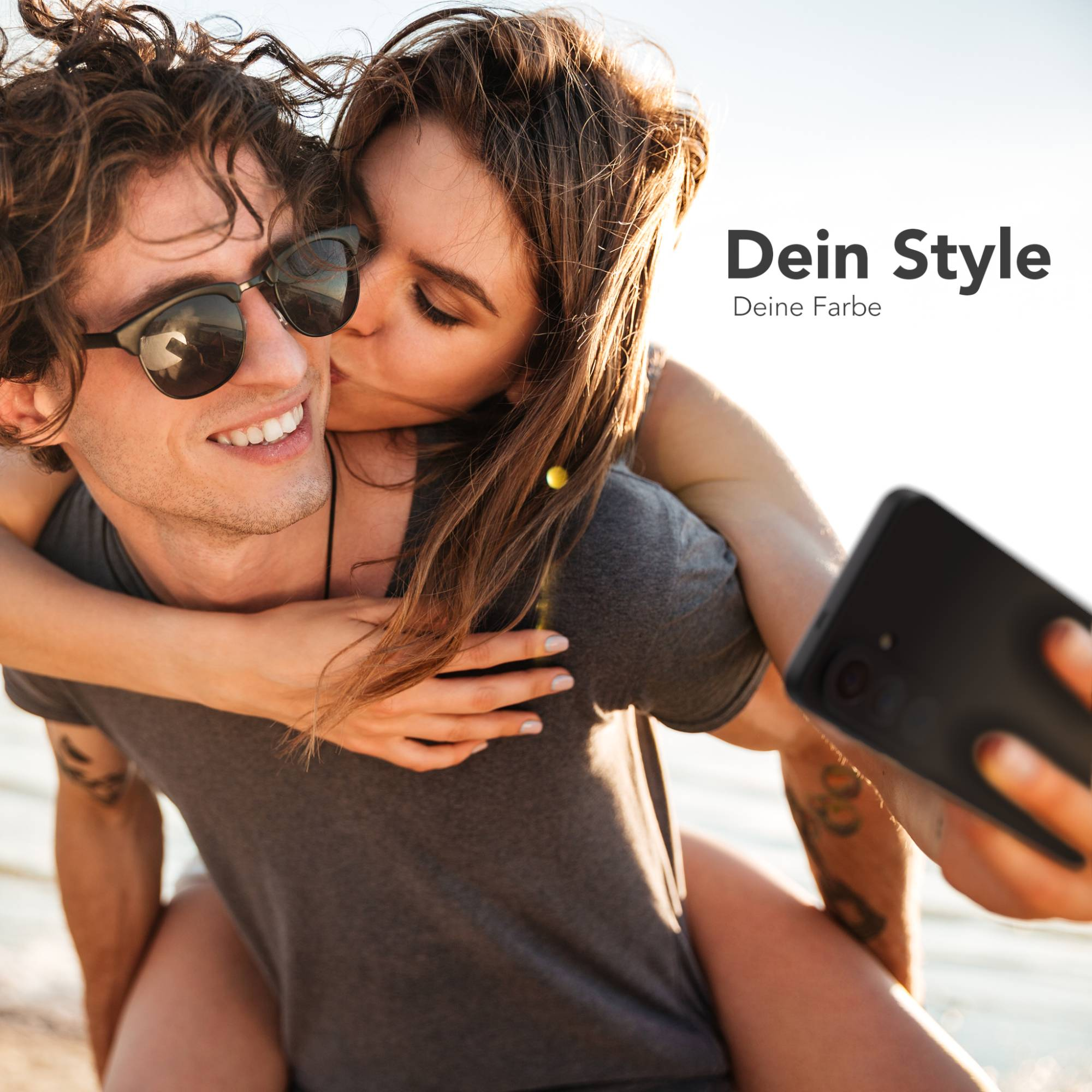Mann mit Sonnenbrille nimmt Selfie mit Freundin, die ihn auf dem Rücken trägt.