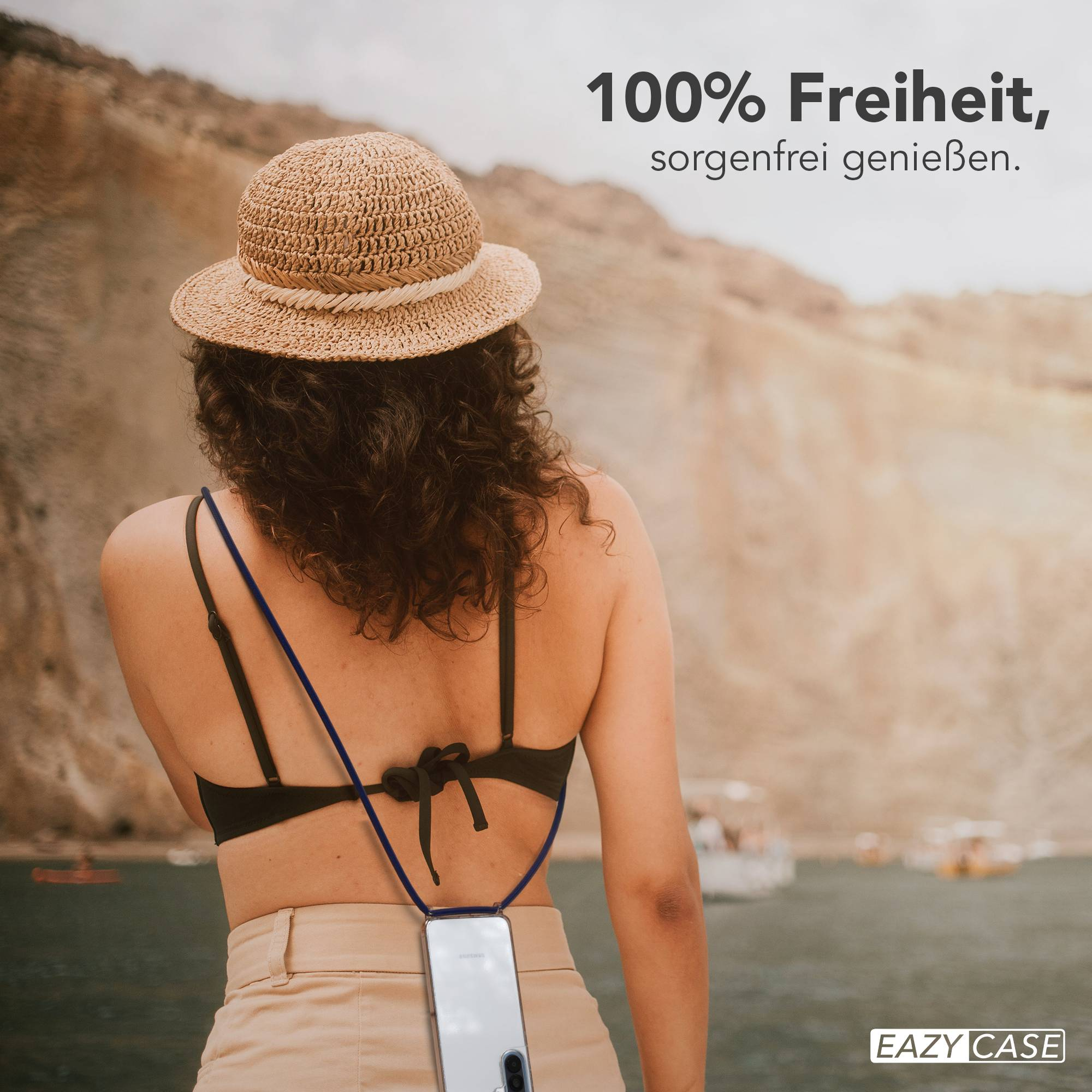 Frau mit Strohhut und Handy-Halterung am Rücken vor Bergen und Wasser.