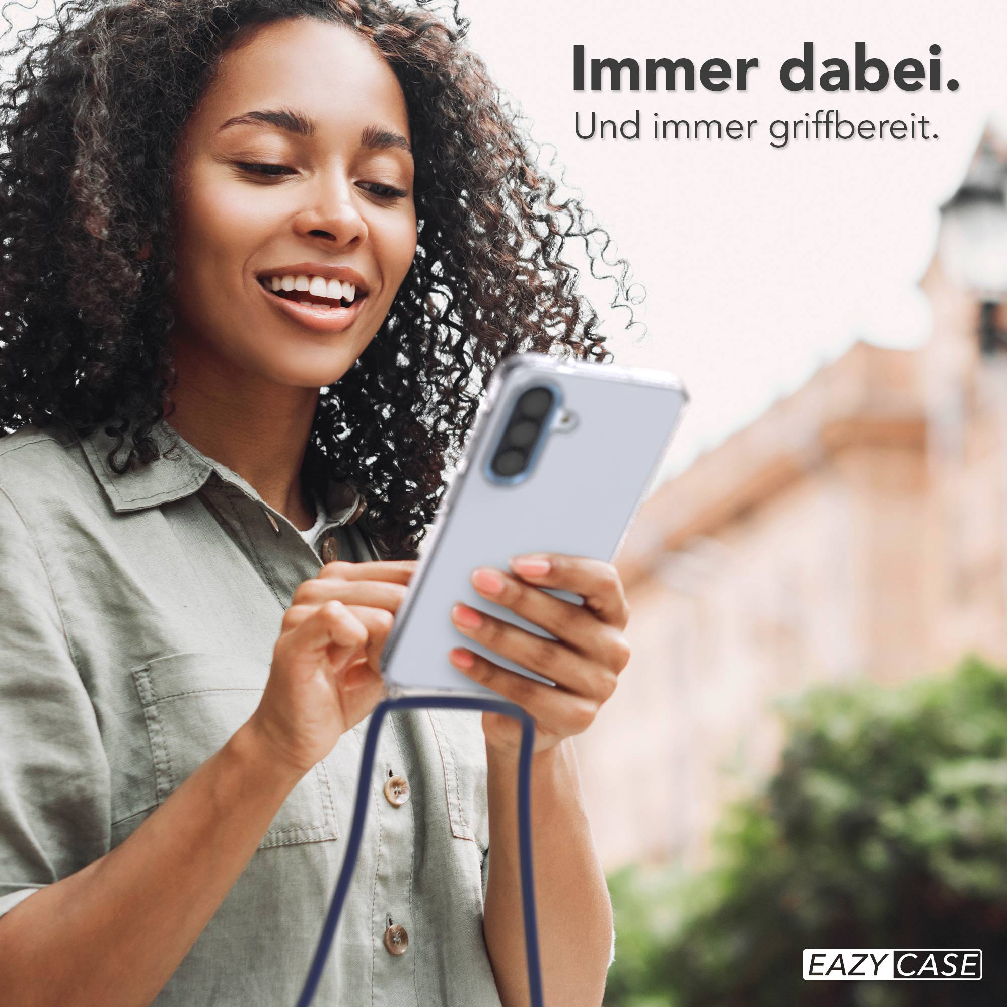 Frau mit lockigem Haar hält ein Handy, das mit einer blauen Schnur verbunden ist.
