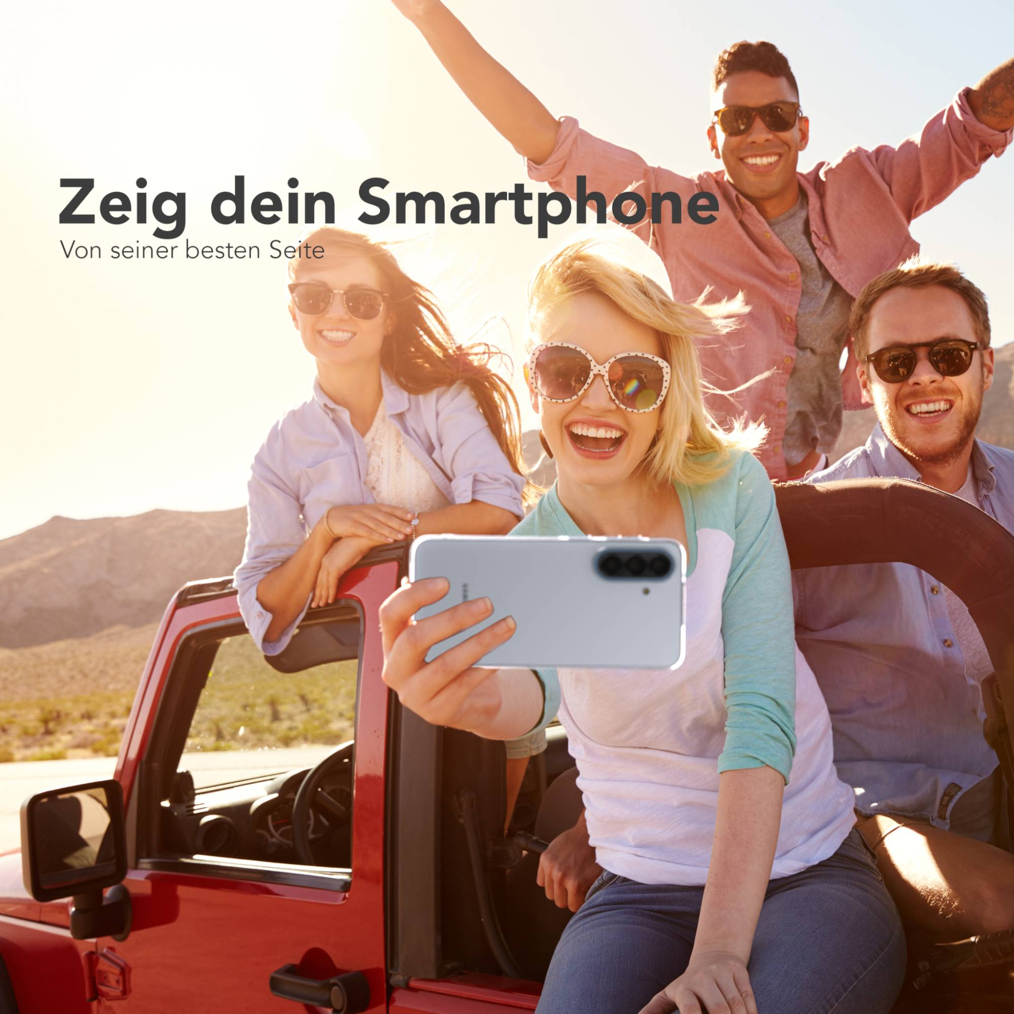 Vier Freunde machen ein Selfie mit einem Smartphone in einem offenen Geländewagen.