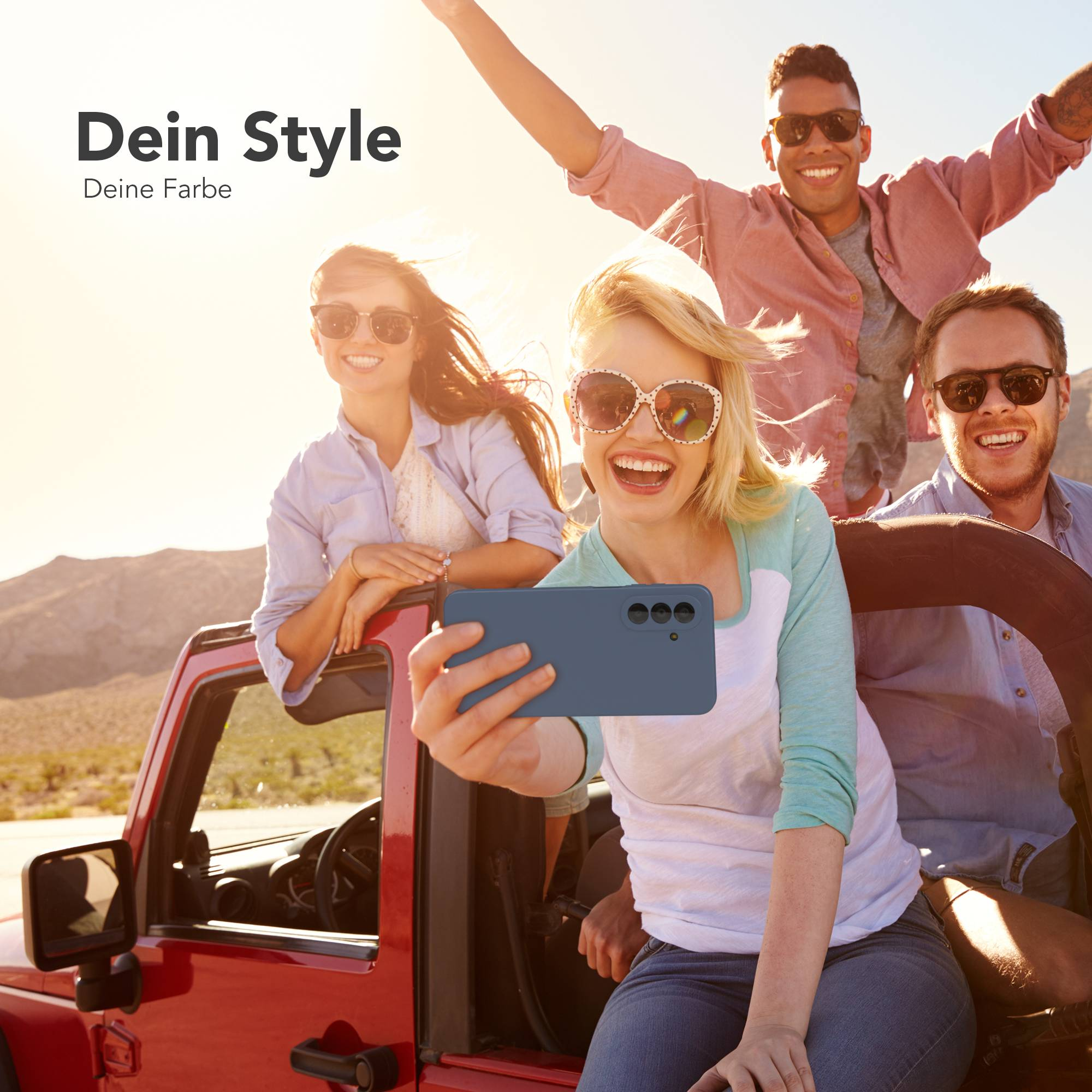Freunde machen Selfie in rotem Jeep, Wüste. Text: Dein Style, Deine Farbe.