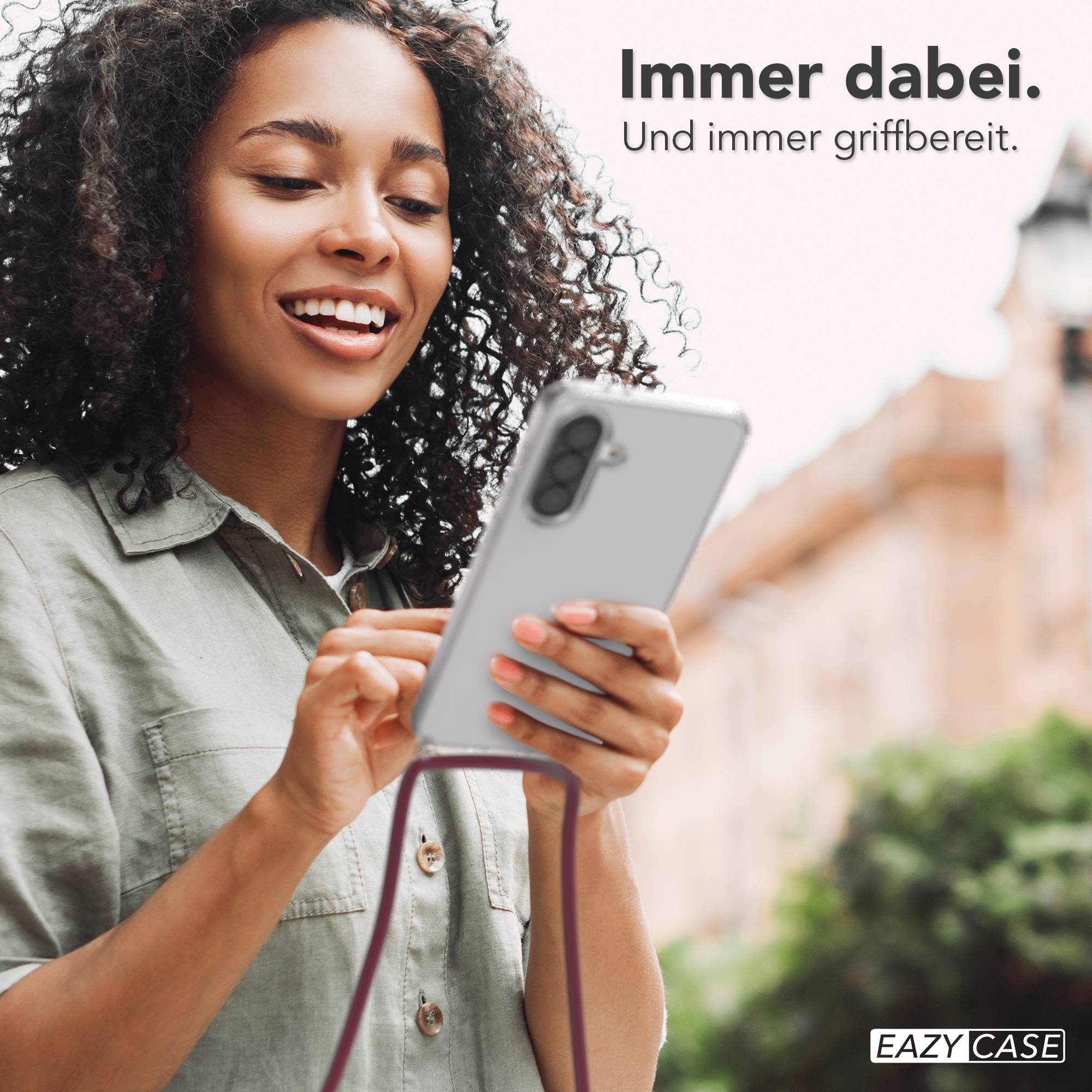 Eine Frau mit lockigen Haaren hält ein Smartphone in der Hand.