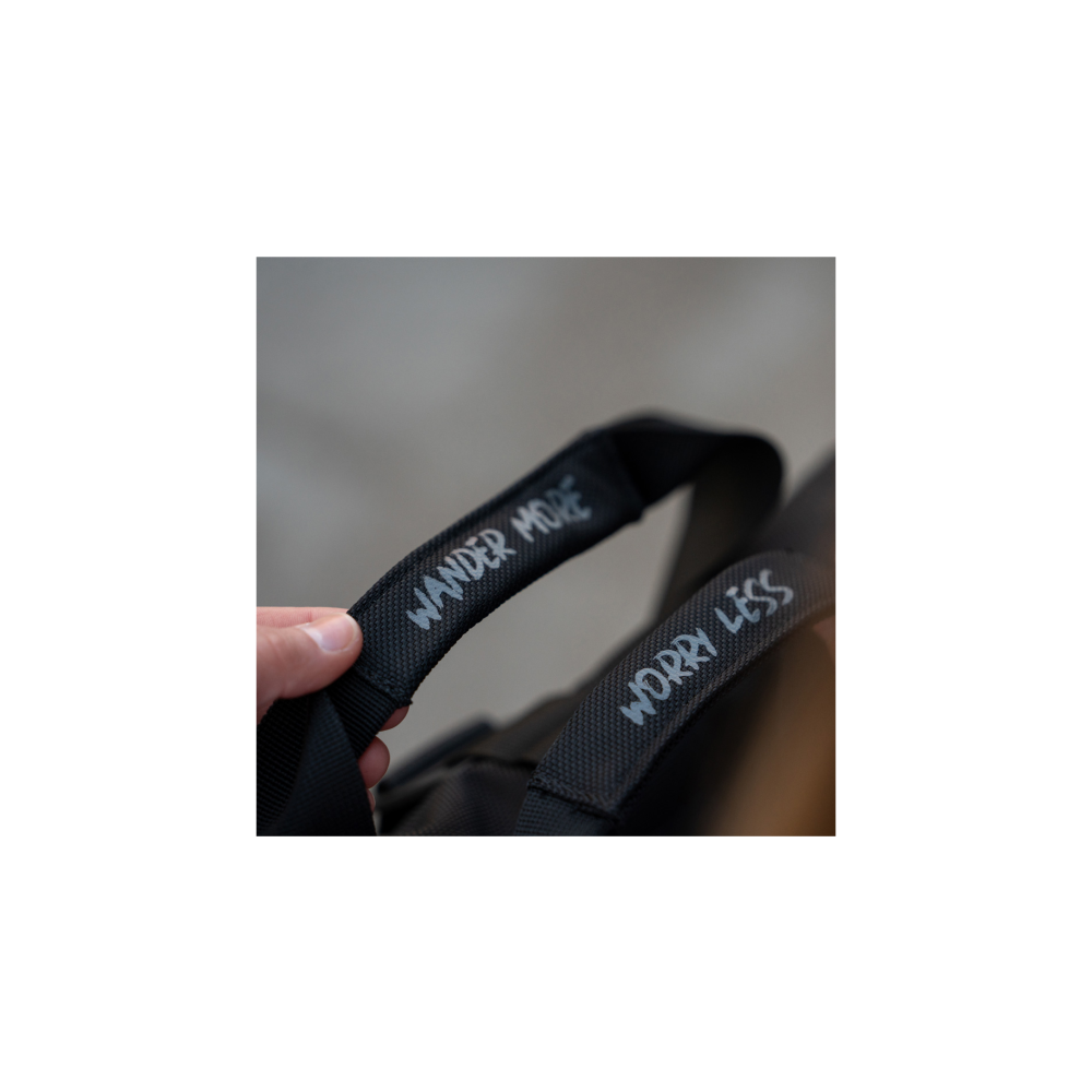 A hand holds a black bag with 'WANDER MORE' and 'Worry LESS' text.