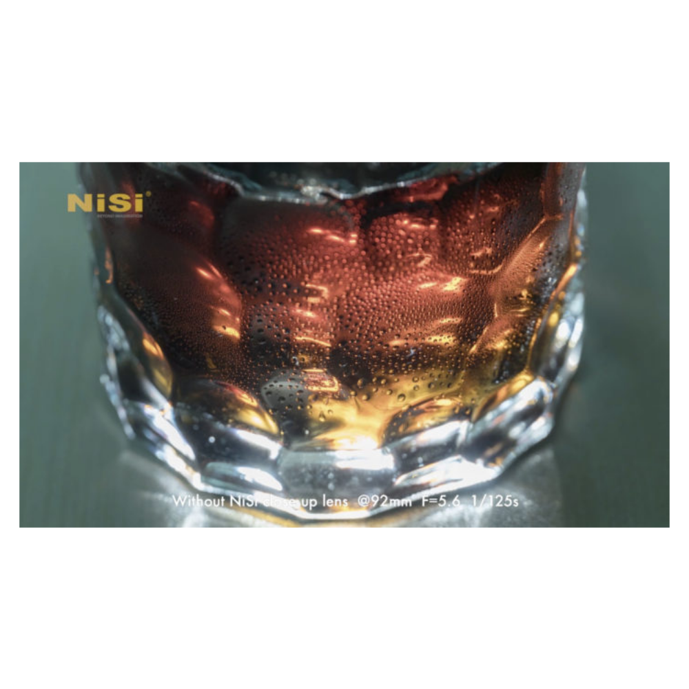 Close-up van glas met bruine vloeistof en waterdruppels. NiSi logo linksboven.