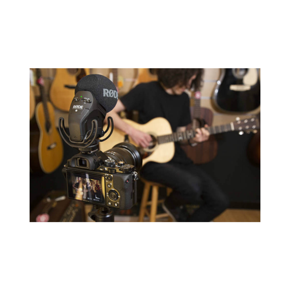 Telecamera con microfono riprende un chitarrista con chitarra acustica in negozio.