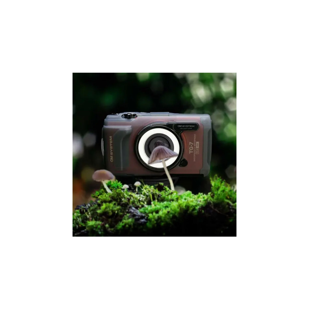 Een digitale camera met macroverlichting zit op mos naast paddenstoelen.