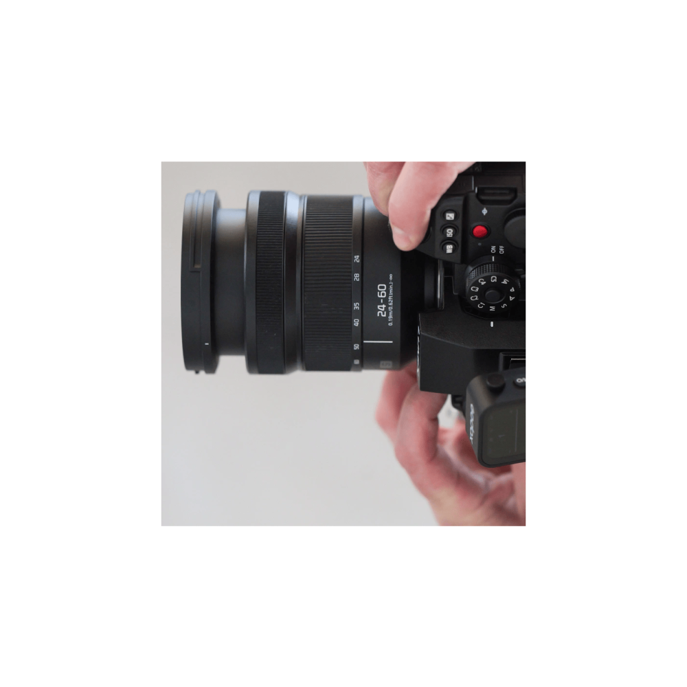 Eine Hand hält ein schwarzes Kameraobjektiv mit Zoommarkierungen 24-60mm.