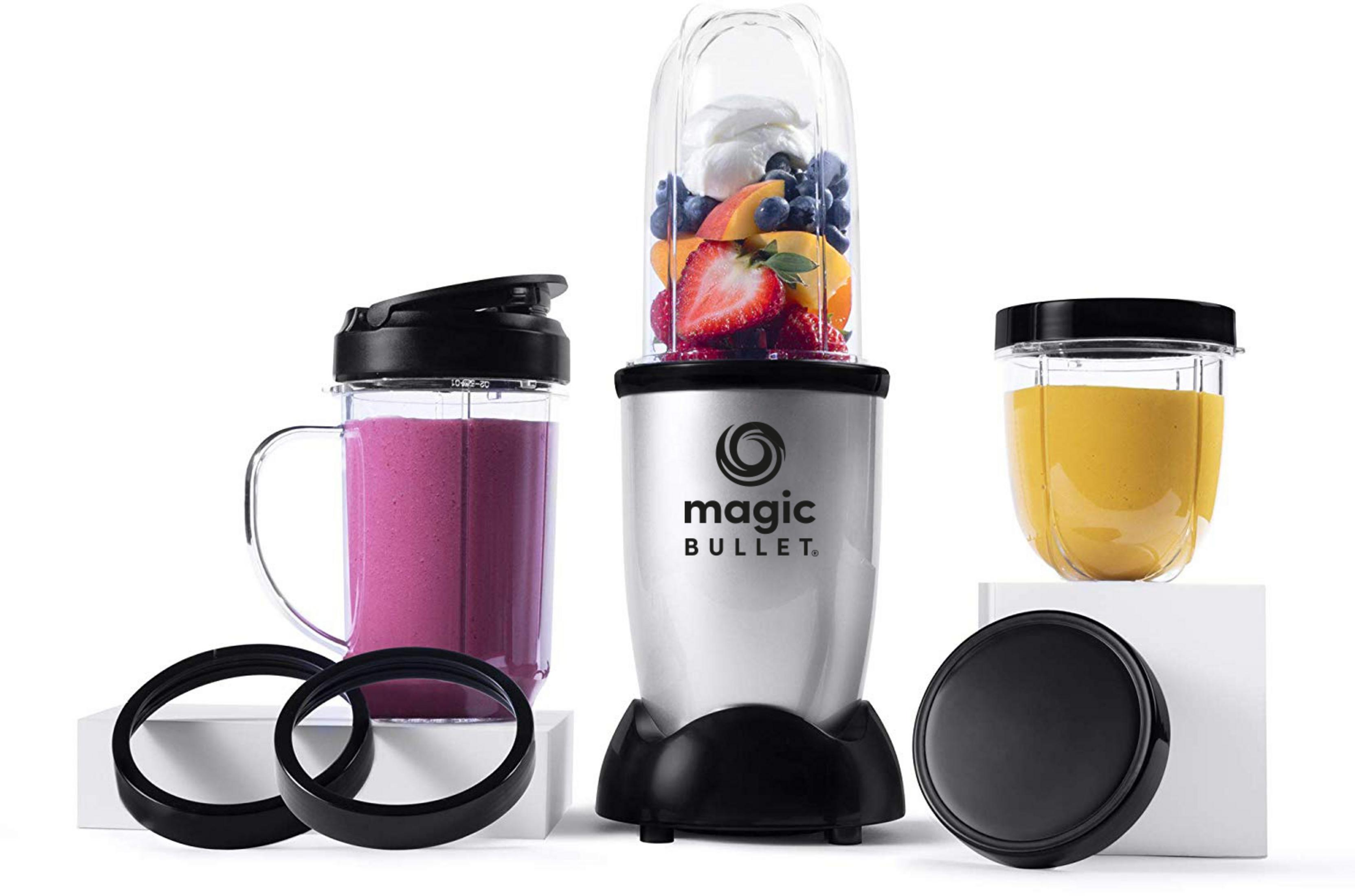 Un mixeur Magic Bullet avec des gobelets à fruits, un avec un smoothie rose, un avec des fruits et un avec un smoothie jaune.