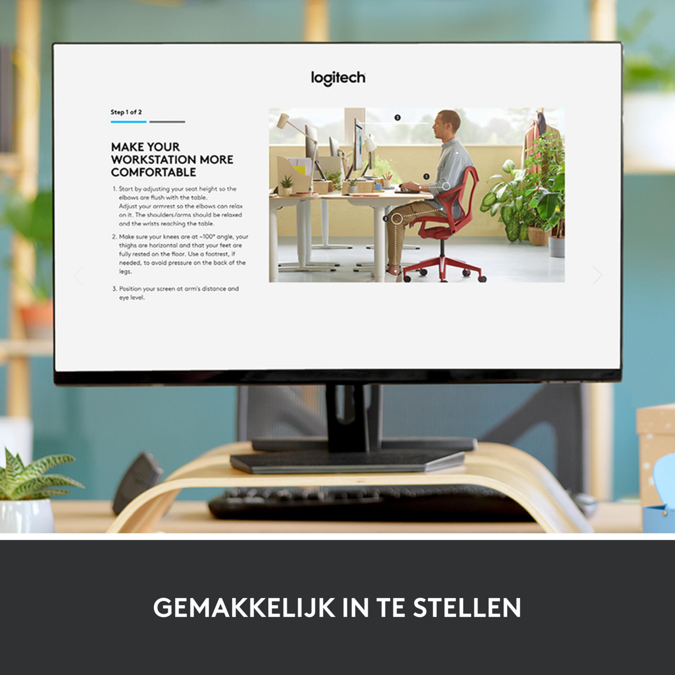 Mężczyzna siedzi przy biurku z dwoma komputerami i roślinami. Instrukcje ergonomiczne.