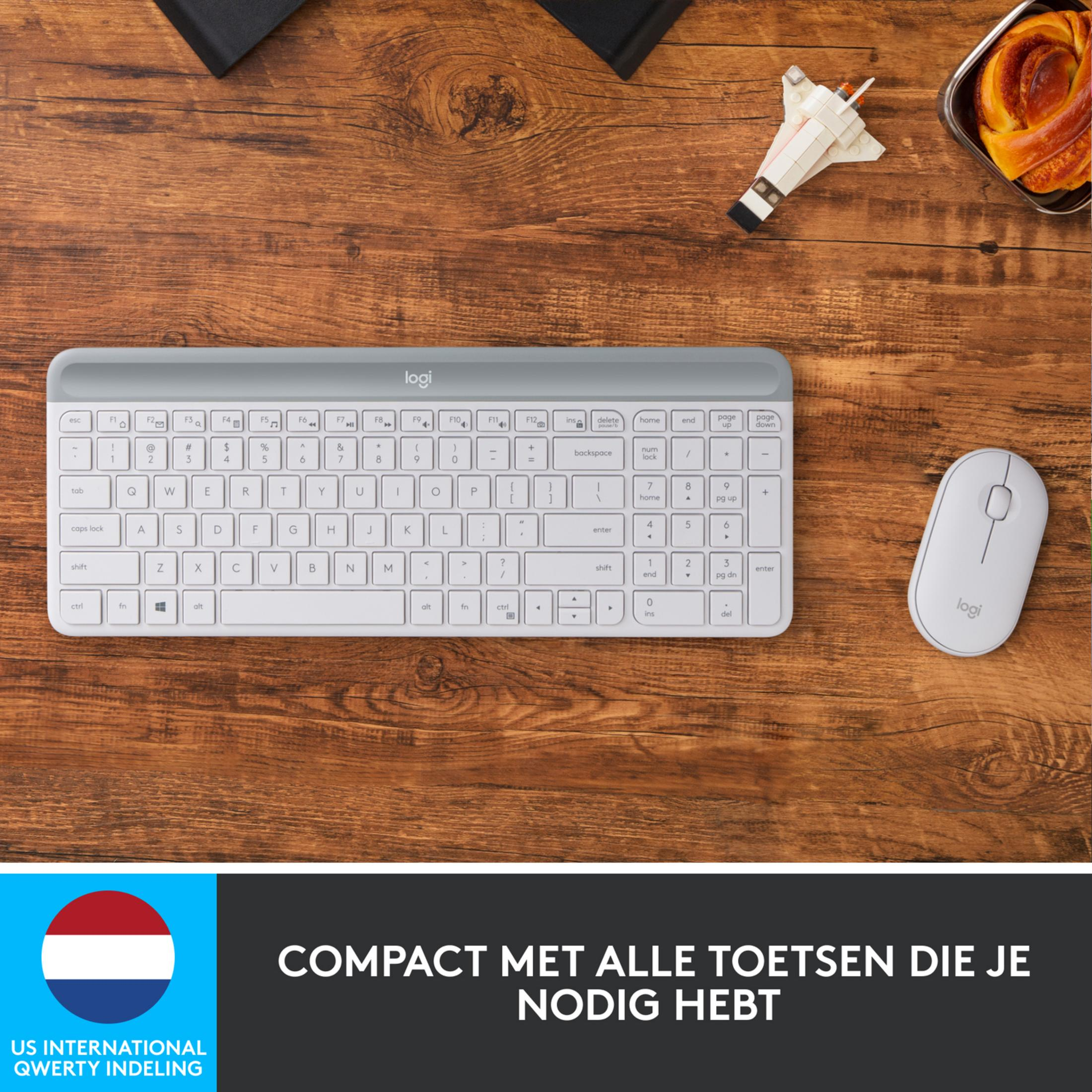 Biała klawiatura i mysz Logitech na drewnie. Z prawej ciasto.