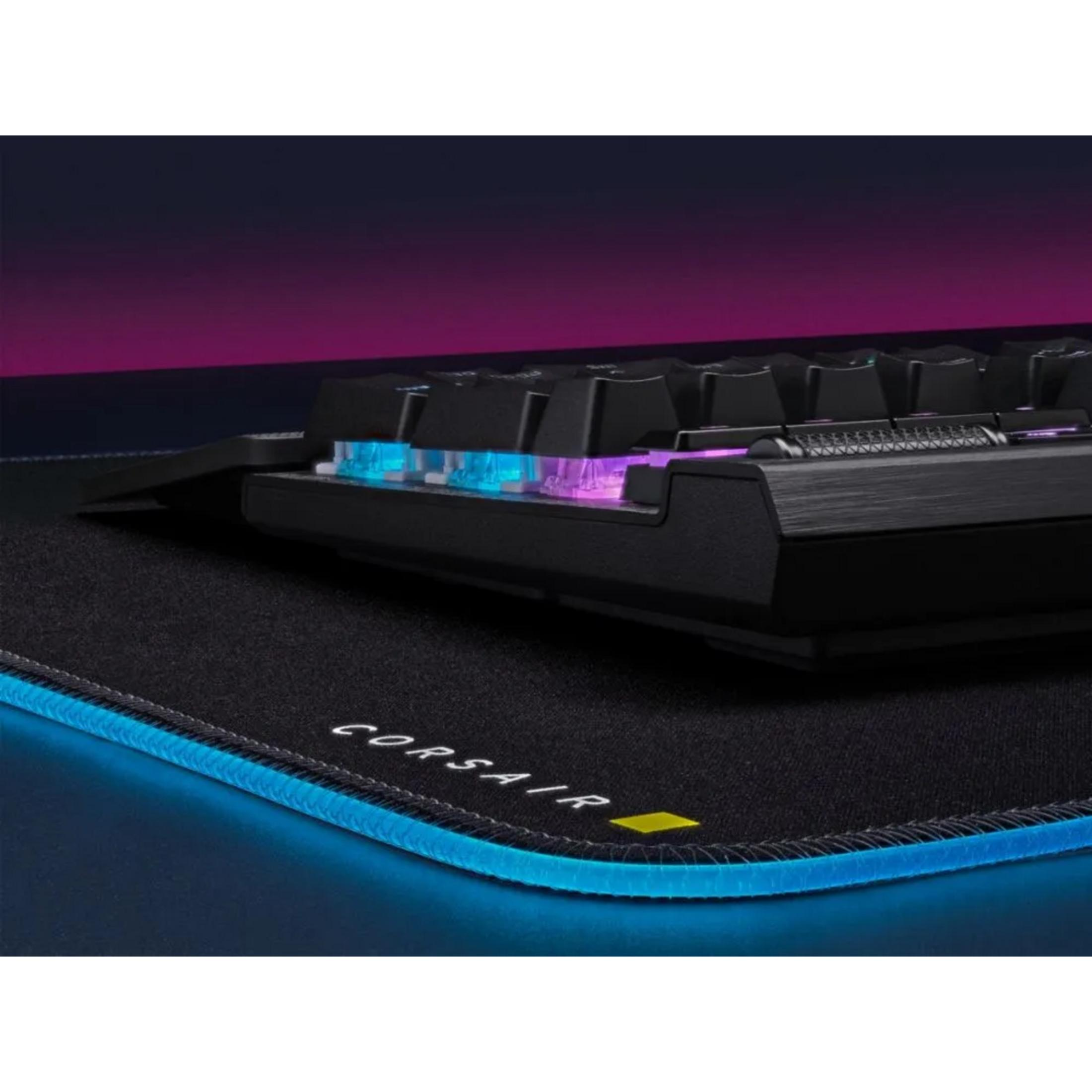 Teclado negro con iluminación RGB azul y morada sobre una alfombrilla negra.