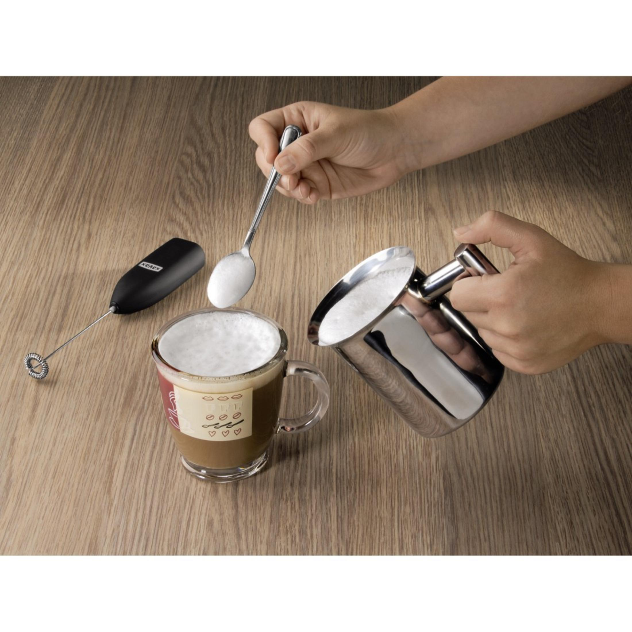 Ein Milchaufschäumer wird über einer Kaffeetasse verwendet, um Zucker hinzuzufügen.