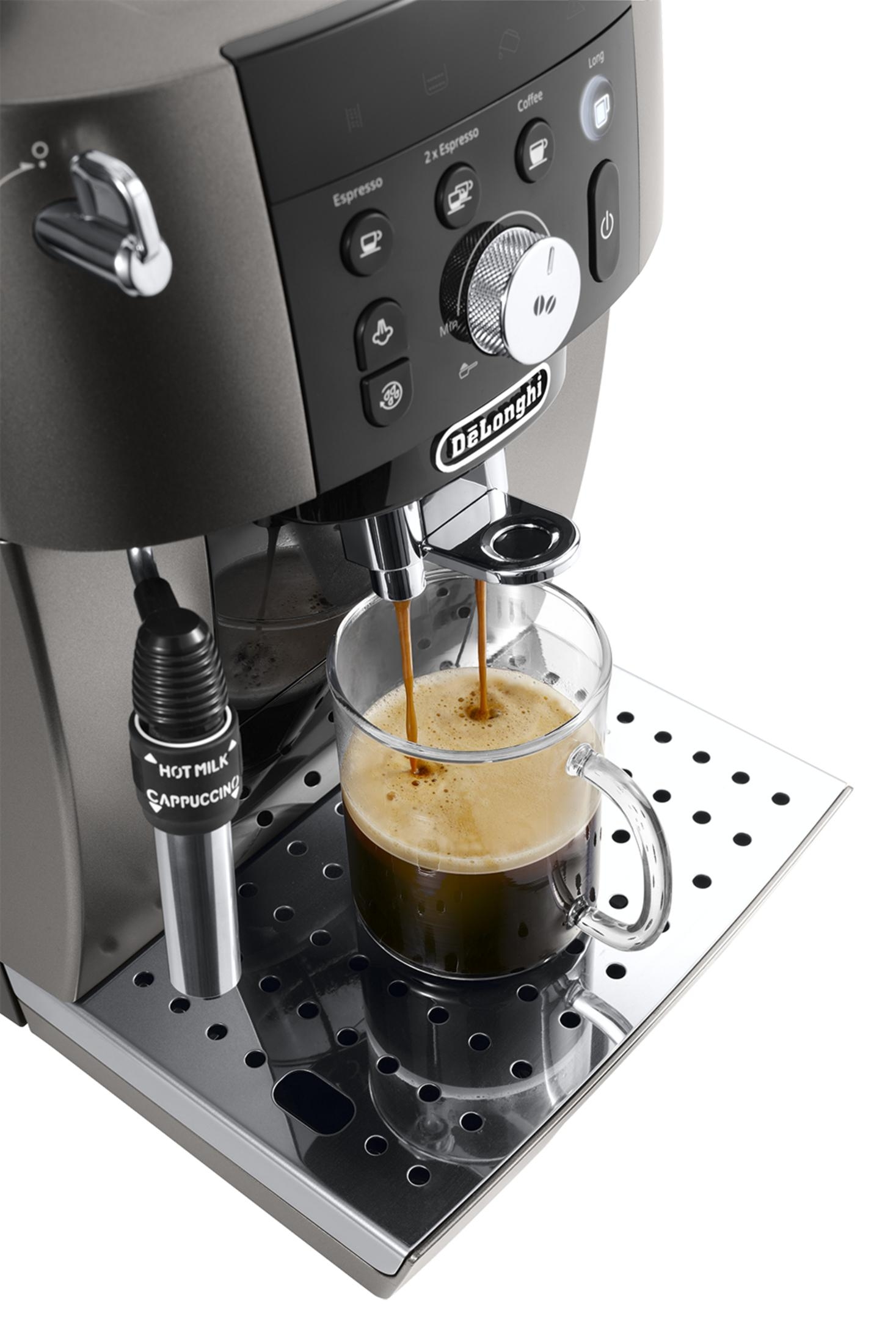 Una máquina de espresso prepara café en una taza de cristal transparente sobre la bandeja de goteo.