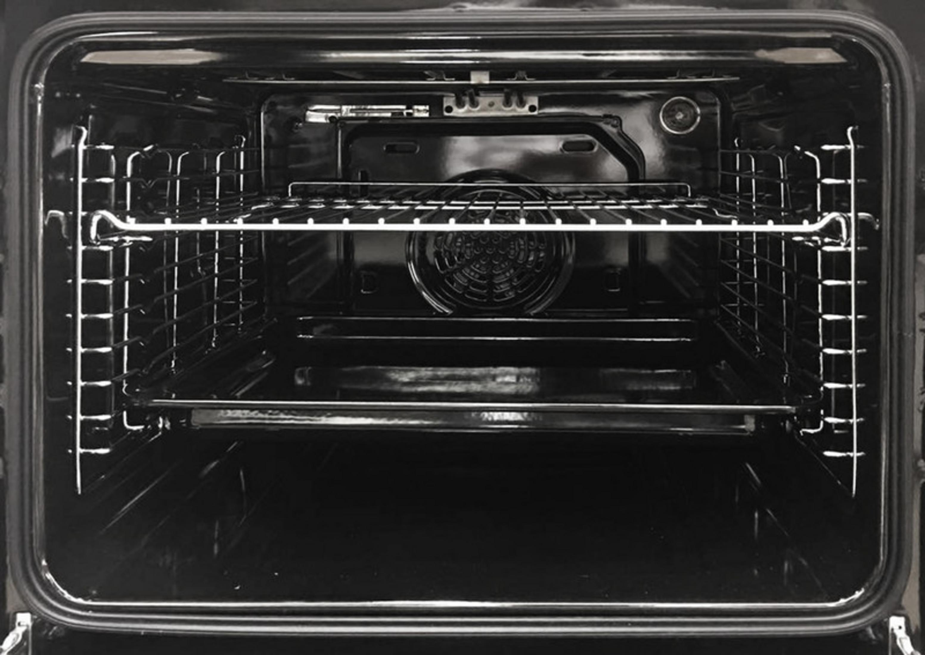 Interior of a clean, black oven with two racks and a fan grille.