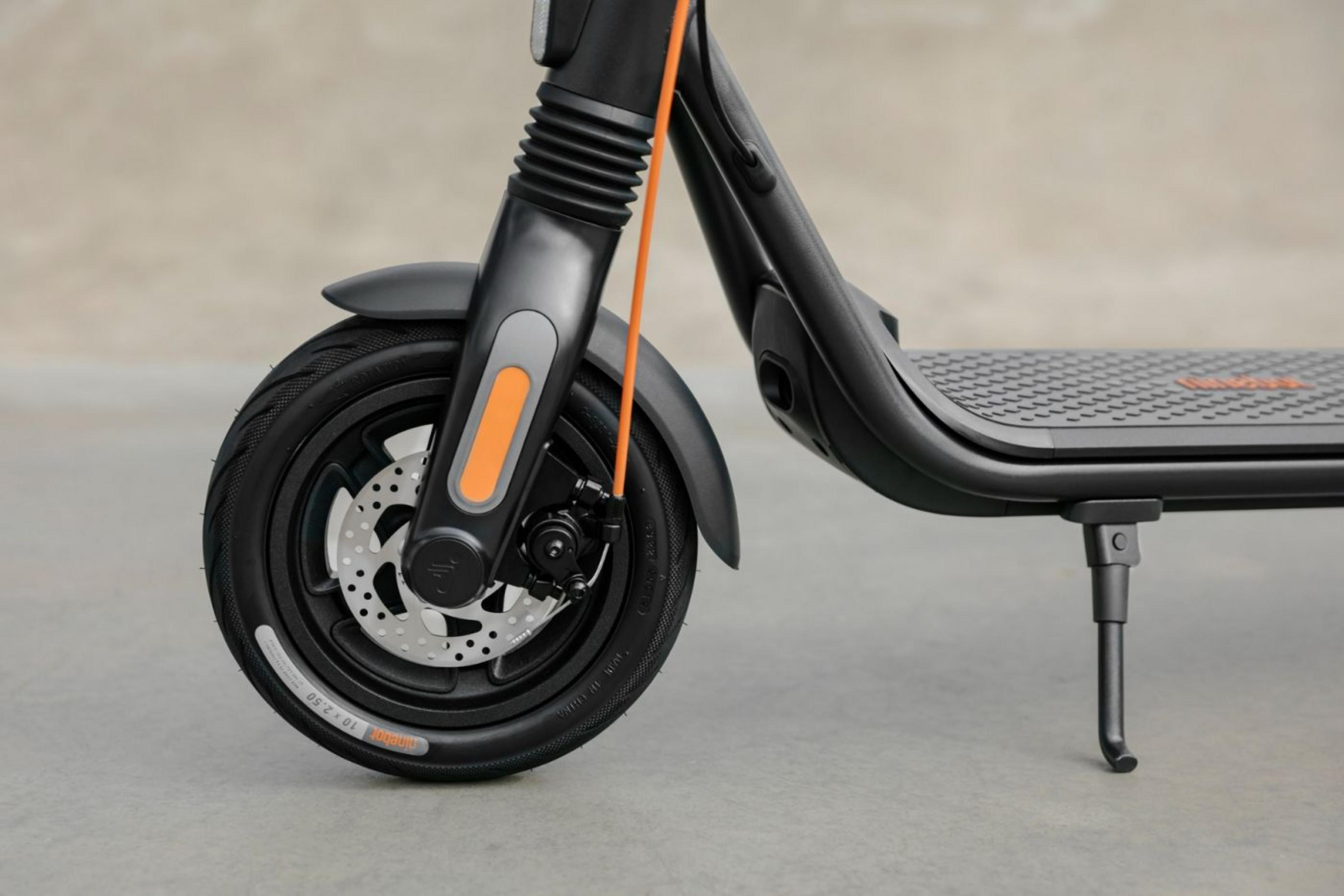 Schwarzer Elektroroller mit orangen Akzenten auf grauem Hintergrund.
