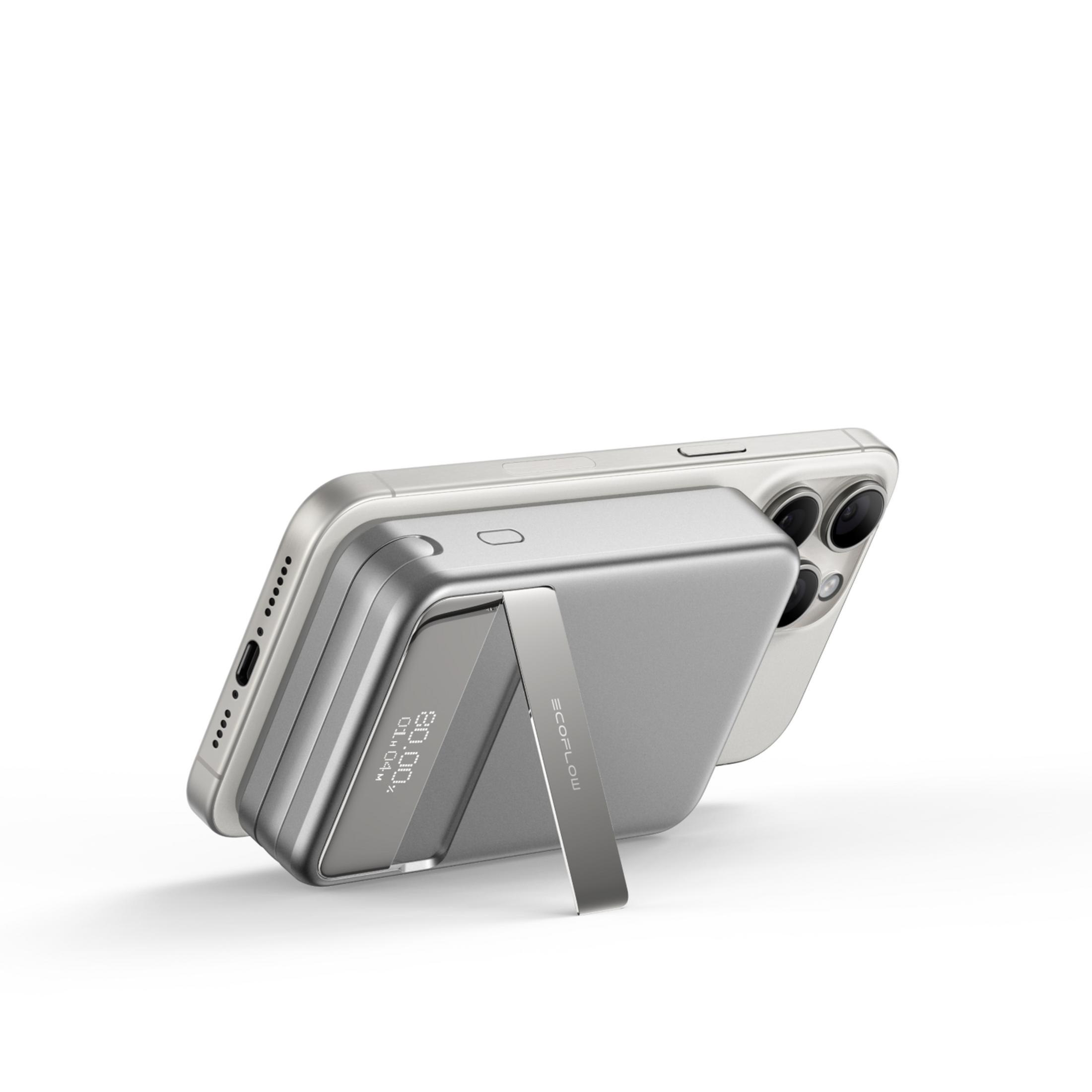 Srebrny iPhone z powerbankiem służącym jako stojak, na białym tle.