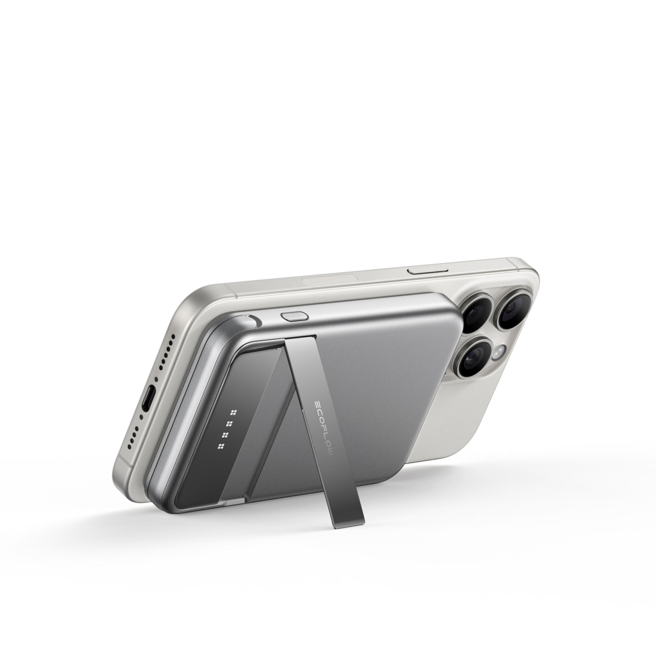 Srebrny smartfon jest przymocowany do szarego magnetycznego powerbanku z podpórką.