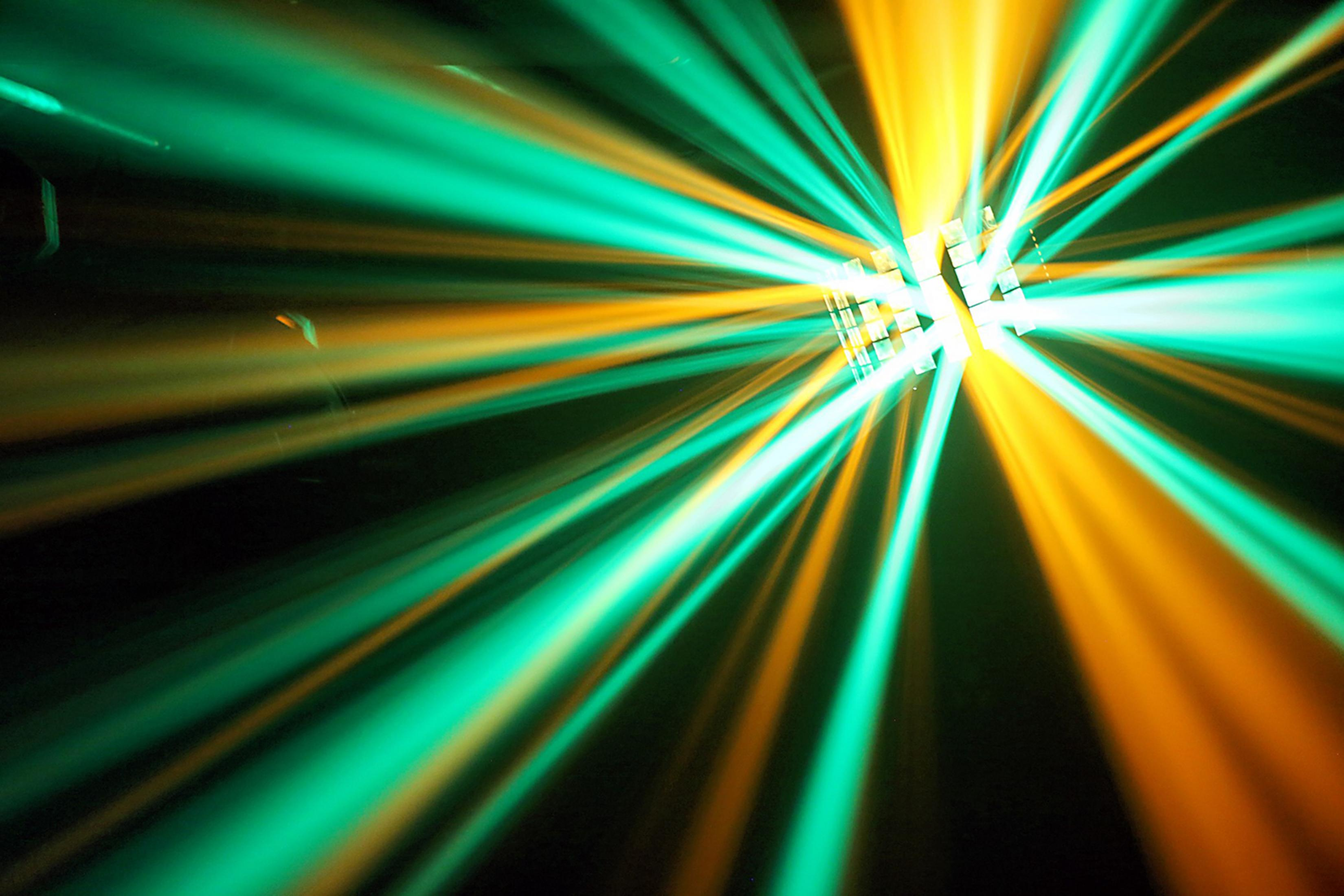 Luces radiantes verdes y naranjas se abren desde un punto central.