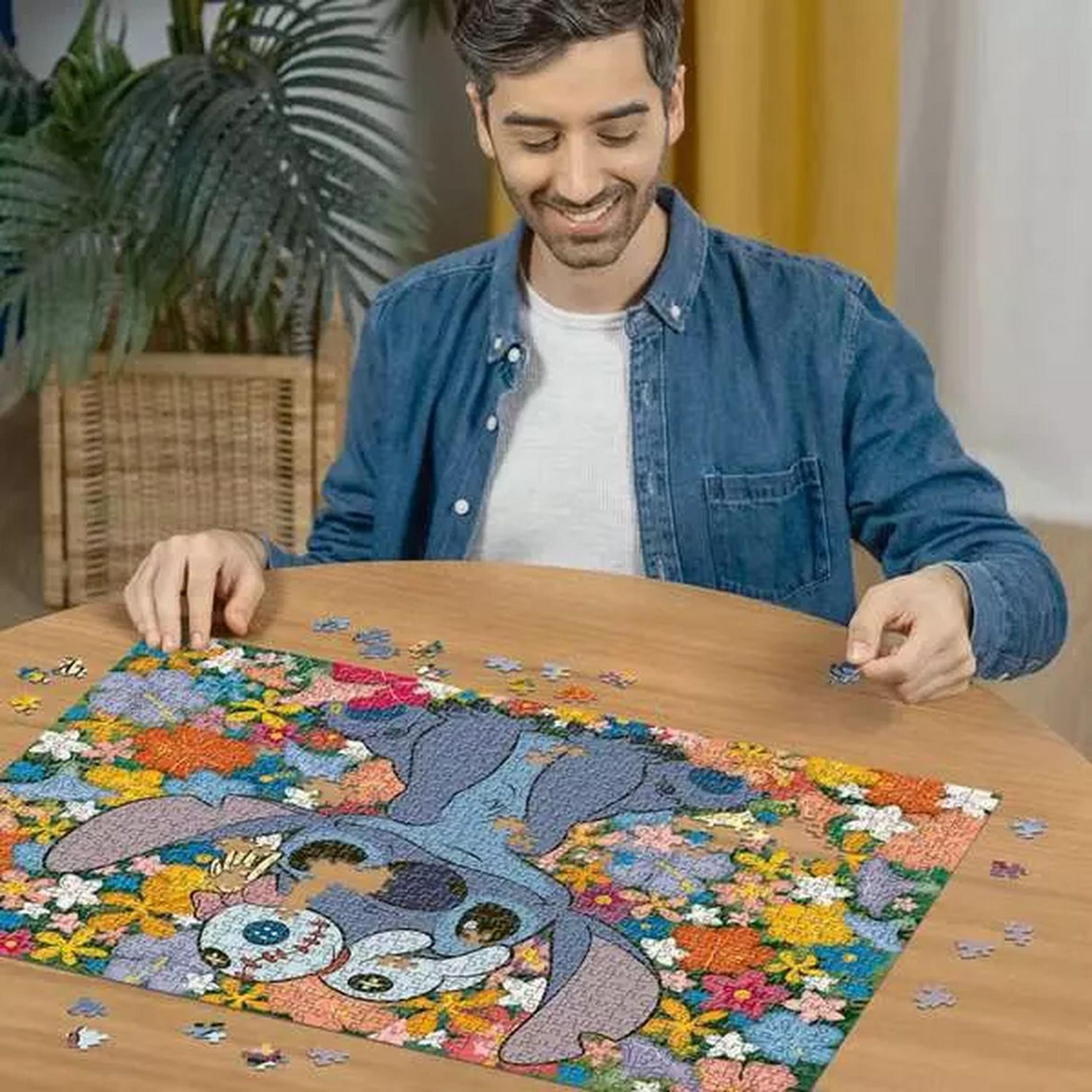 Mężczyzna w dżinsowej kurtce układa kolorowe puzzle Stitch z kwiatami na drewnianym stole.