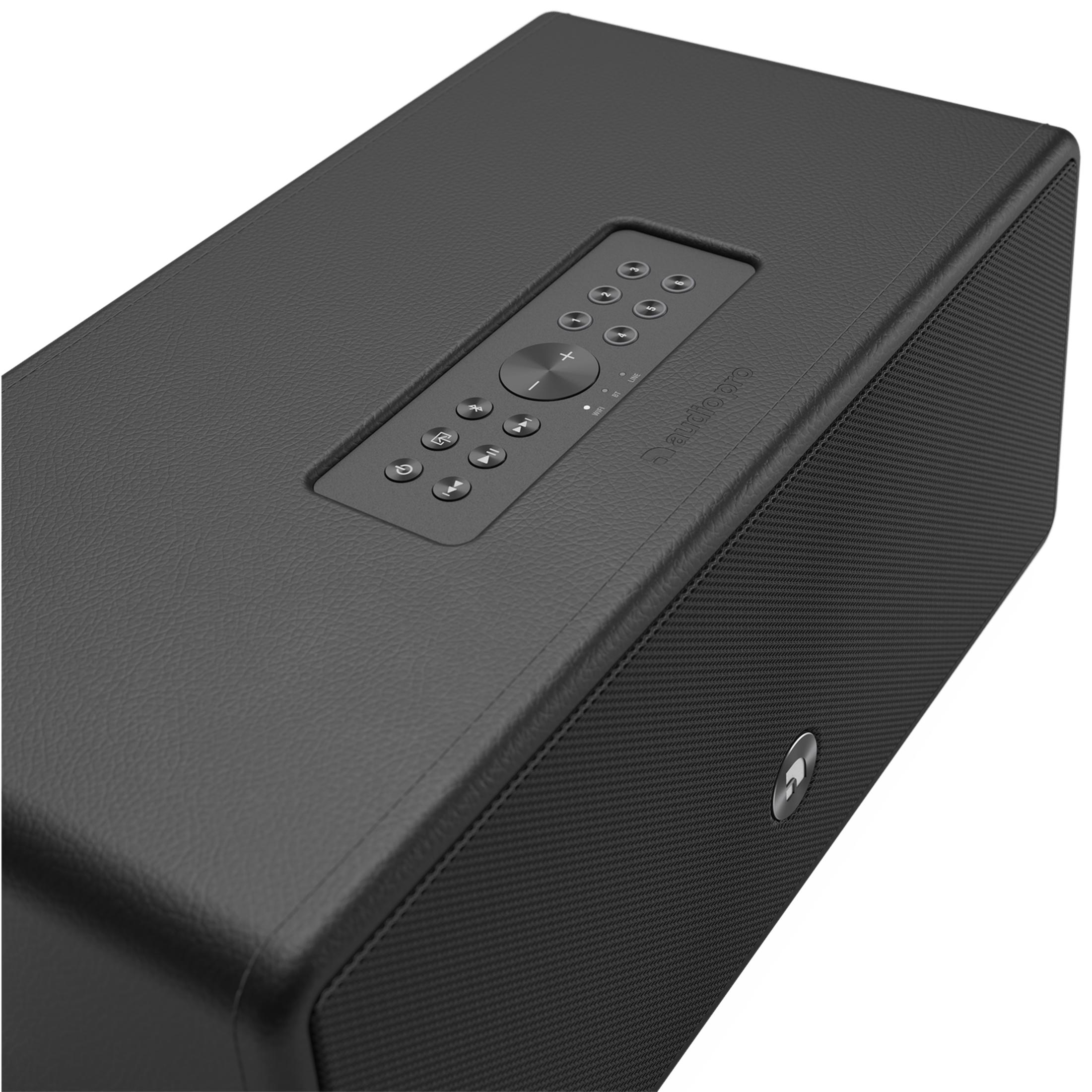 Black textured speaker with top control panel. White background.