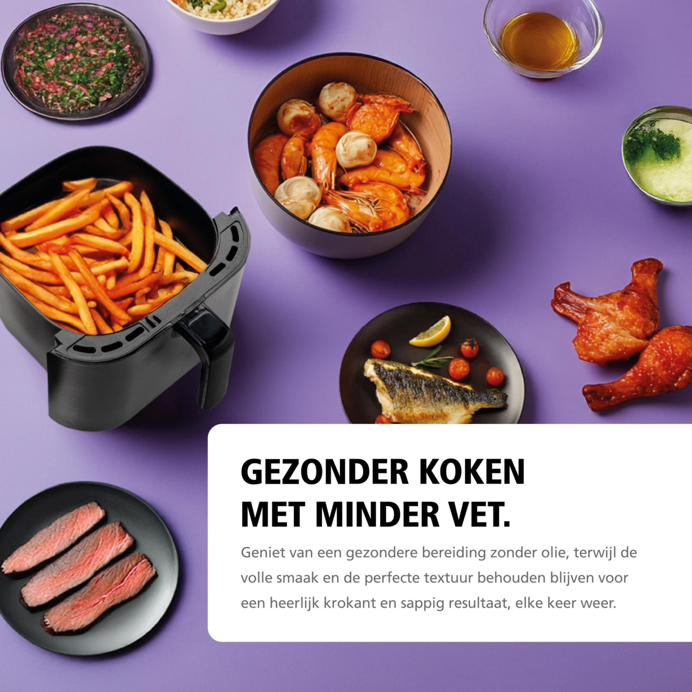 An air fryer with fries, meat, fish, and shrimp on a purple background.