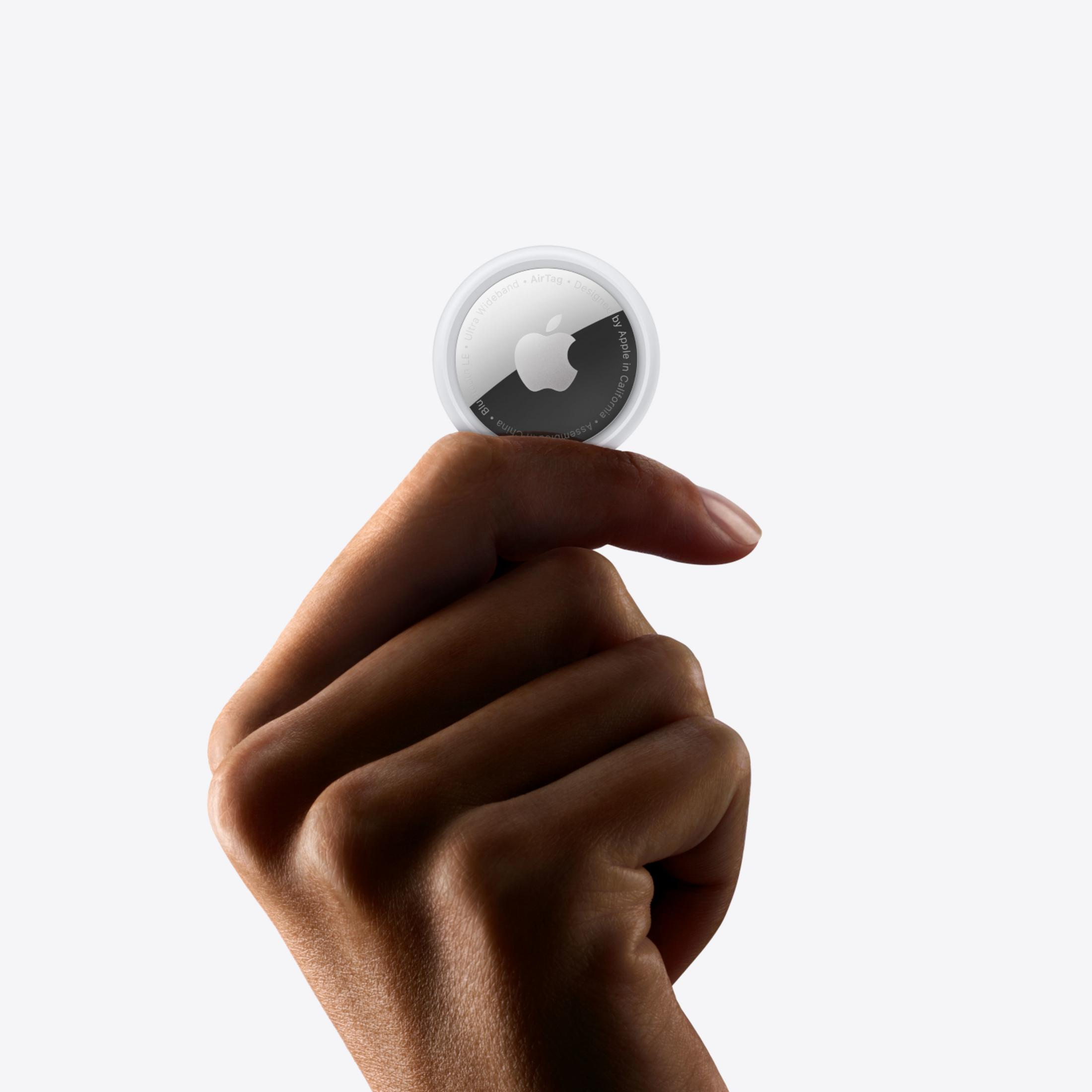 Dłoń trzyma biały Apple AirTag z logo Apple.
