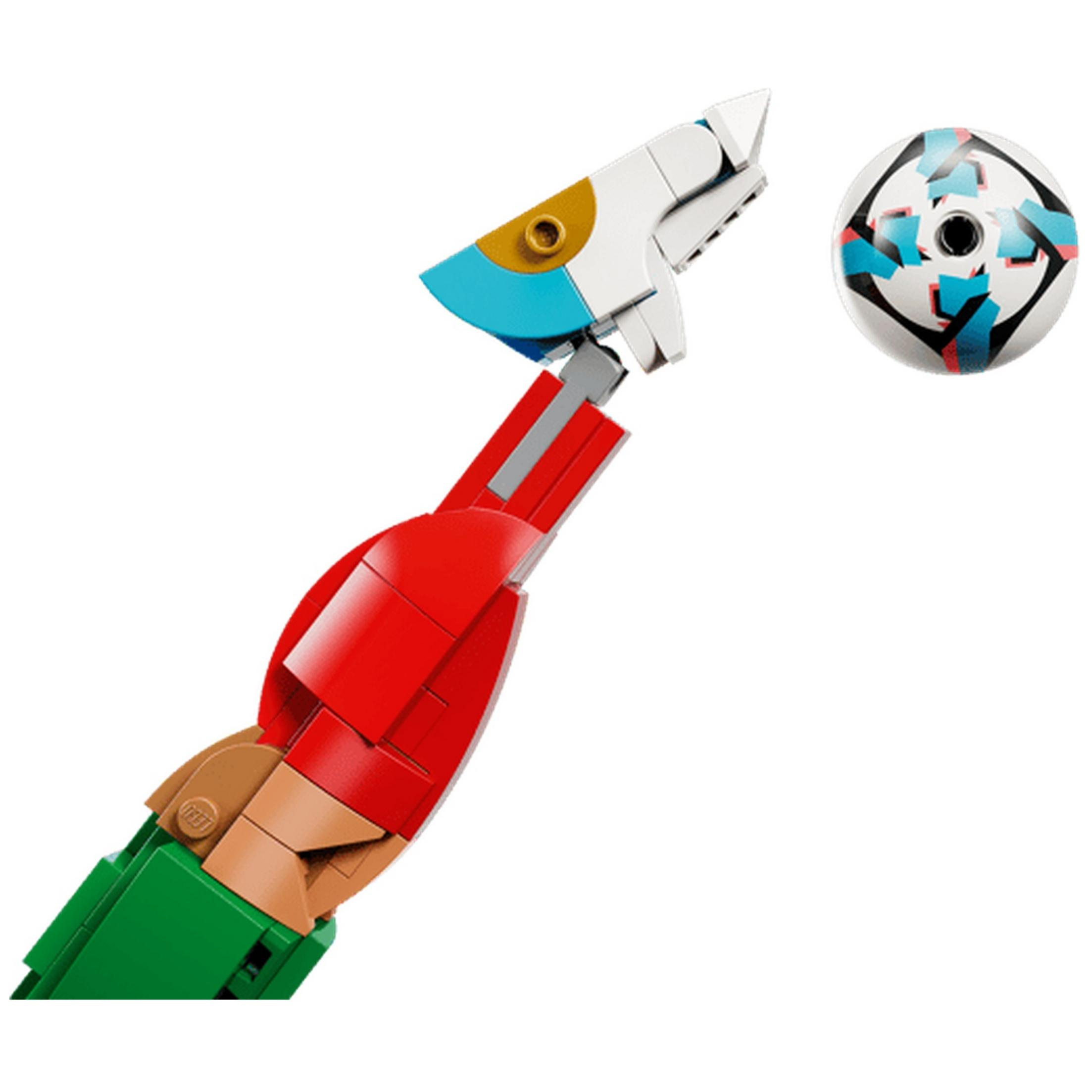 Kırmızı ve yeşil Lego kolu, bir futbol topunu hedef alıyor.