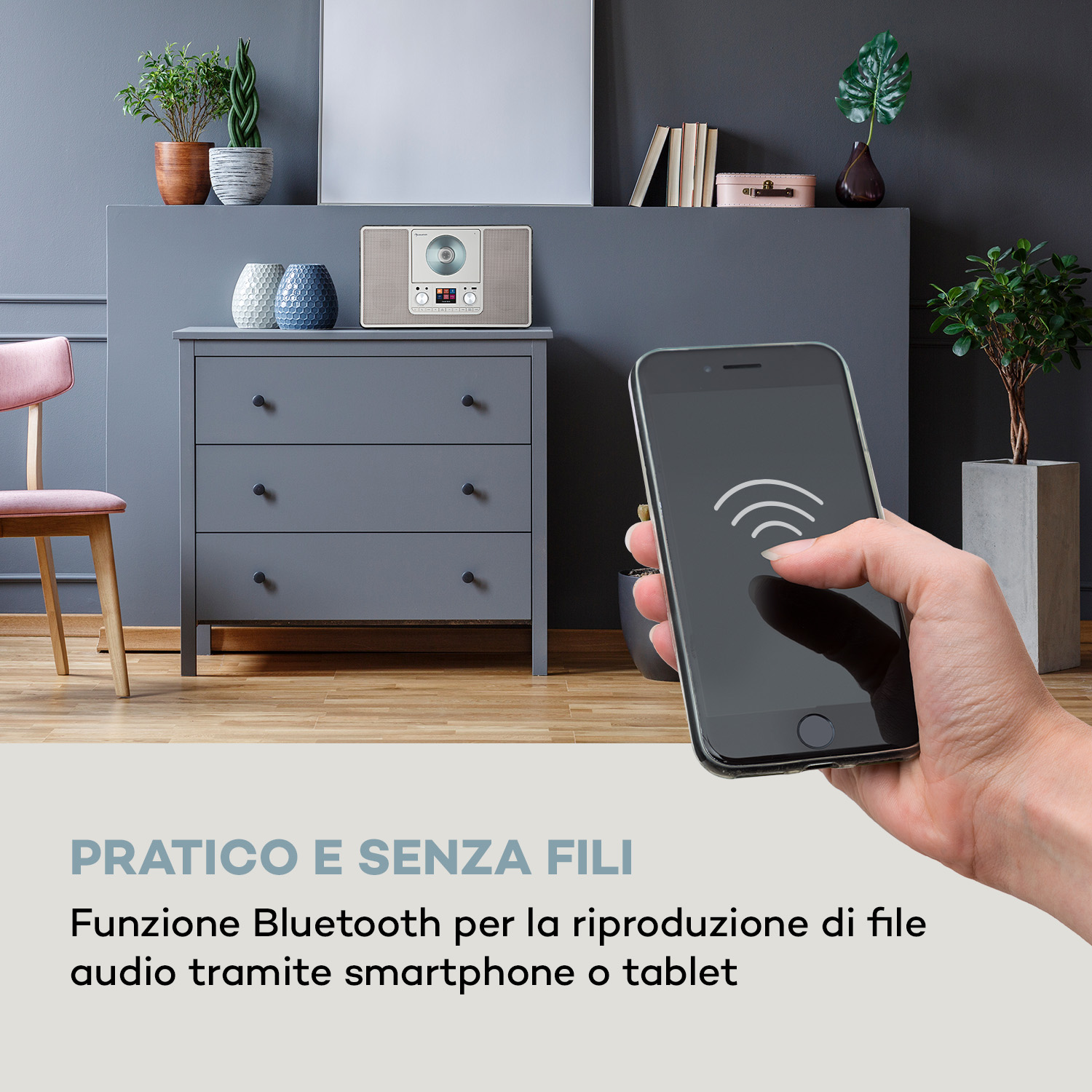 Hand hält Smartphone mit Bluetooth-Symbol vor einem Radio auf einer Kommode.