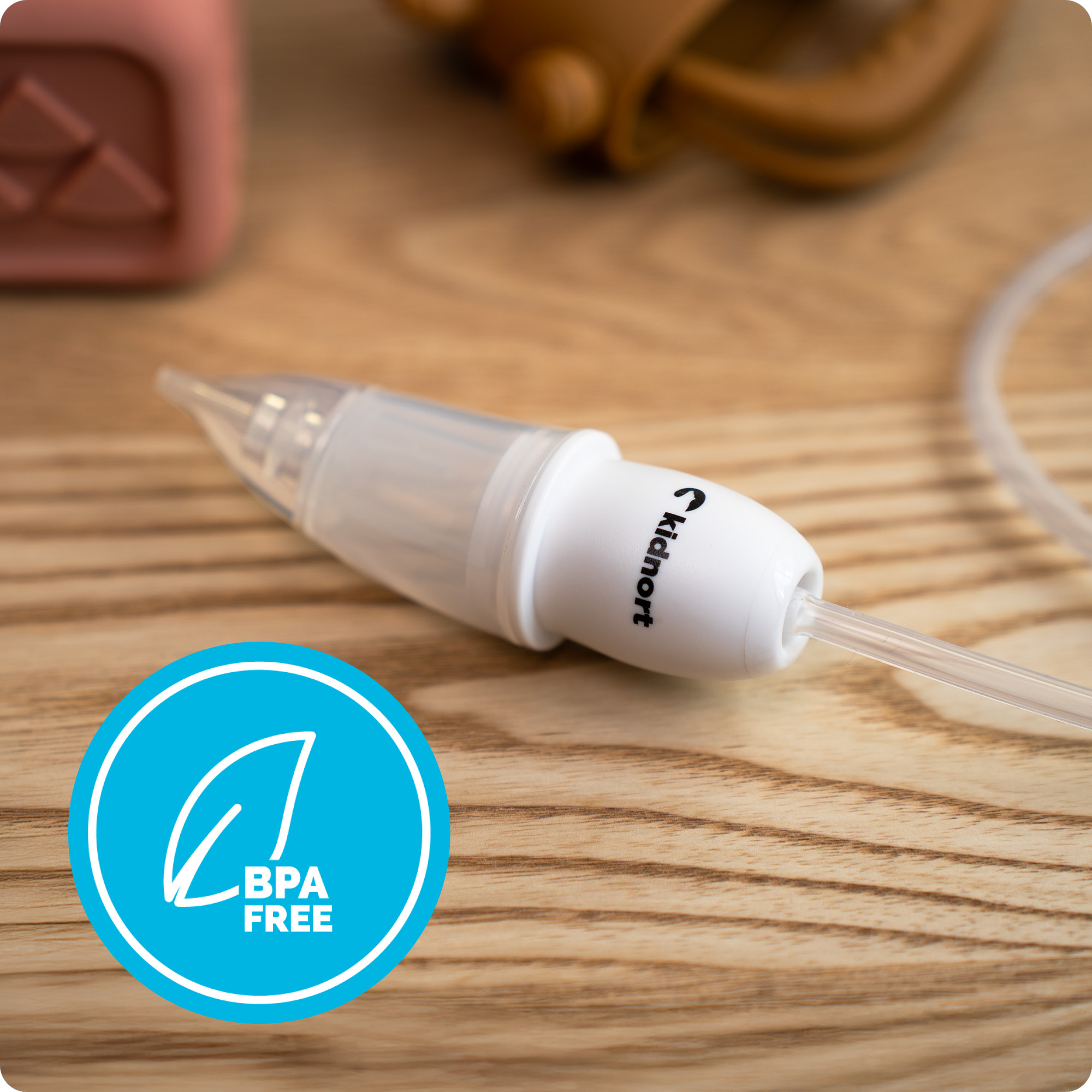 Aspirator nosowy z oznaczeniem BPA-free na drewnianym tle.