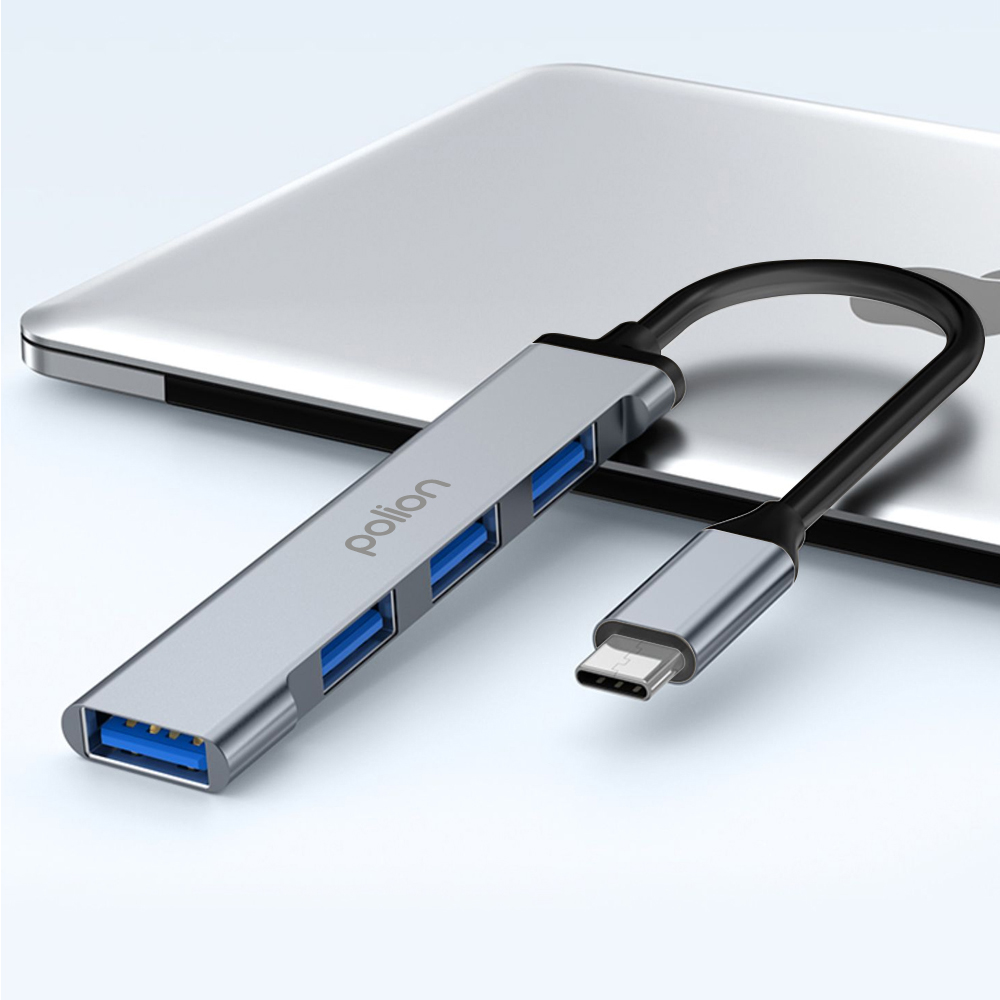 Srebrny hub USB-C z czterema niebieskimi portami USB leży na laptopie.