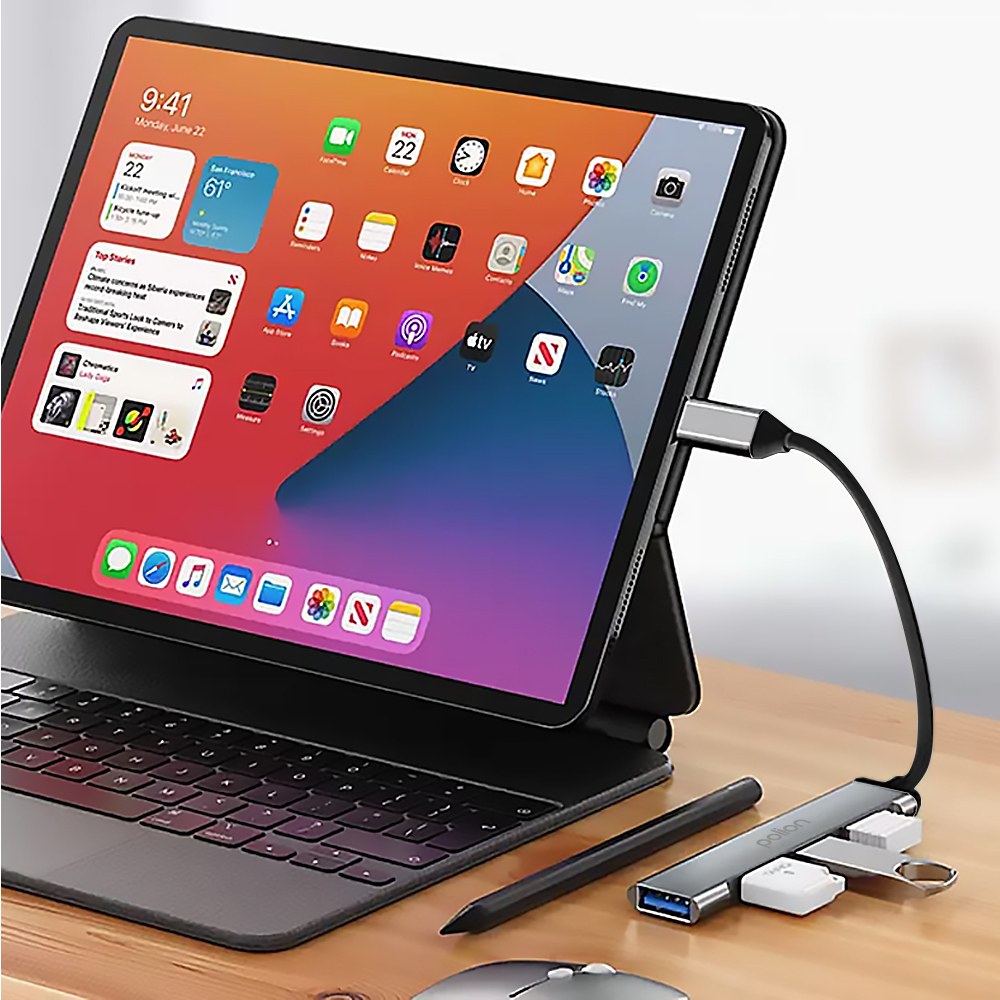 Tablet z klawiaturą, rysikiem i hubem USB na drewnianym biurku.