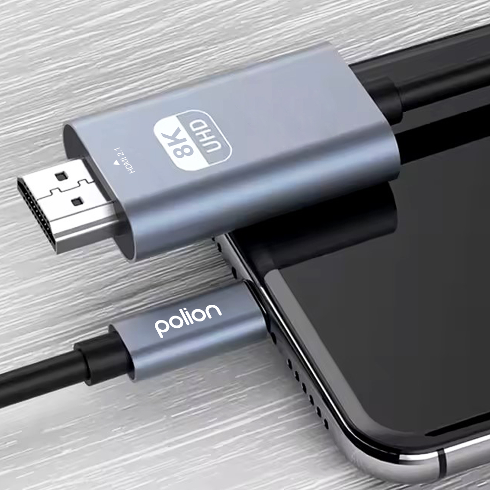 Szary adapter HDMI z oznaczeniem 8K UHD jest podłączony do smartfona.