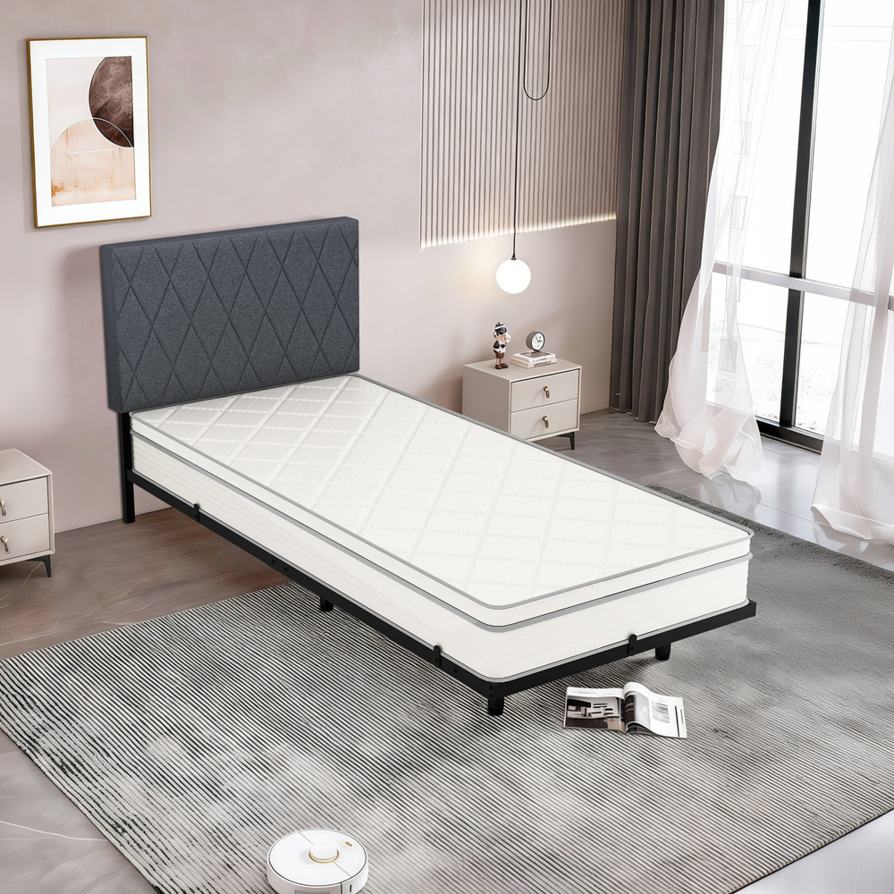 Ein schmales Bett mit weißer Matratze und dunklem Kopfteil in einem modernen Schlafzimmer.