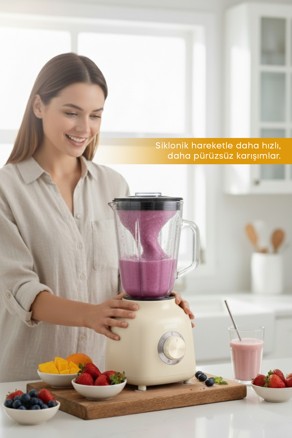 Mor smoothie'li blender kullanan gülümseyen kadın. Tezgahta meyveler.
