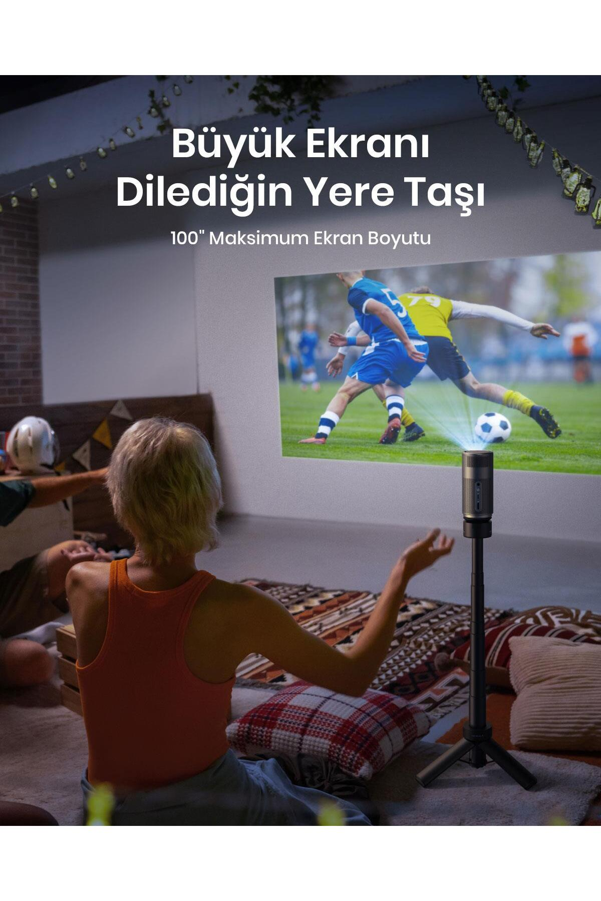 İnsanlar izlerken bir projektör ekrana futbol maçı yansıtıyor.