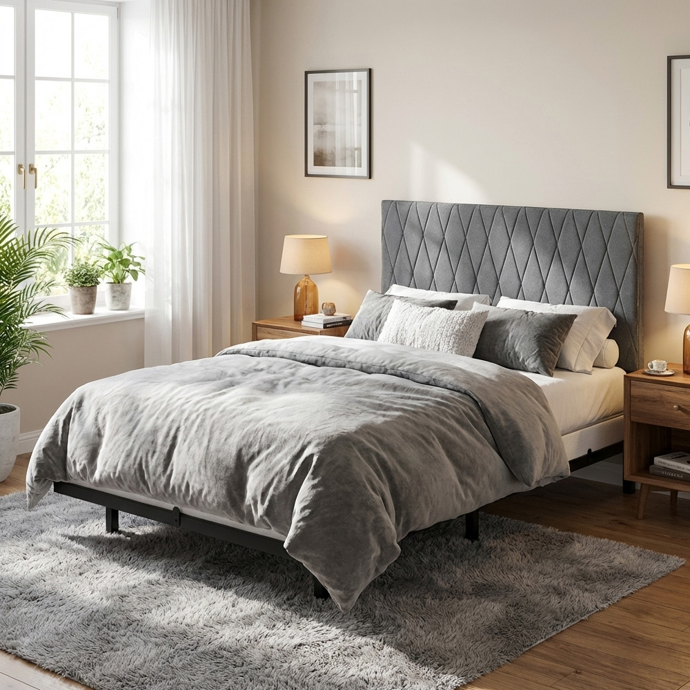 Ein gemütliches Schlafzimmer mit einem großen Bett, grauem Bettzeug und einem Rauten-Kopfteil.