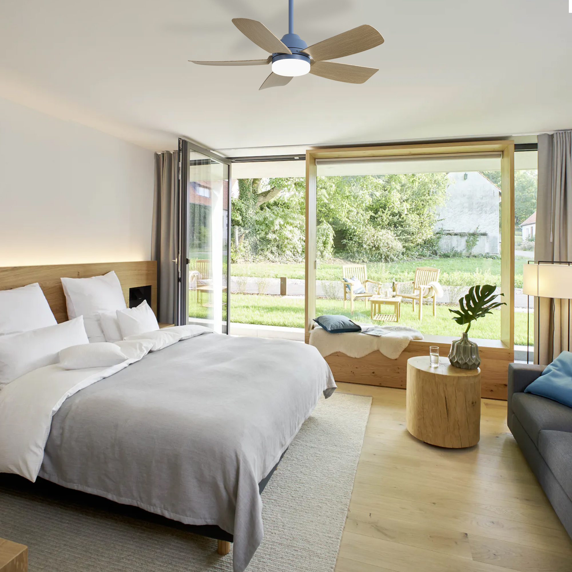 Ein Schlafzimmer mit großem Bett und Blick auf einen Garten mit Sitzgelegenheiten.