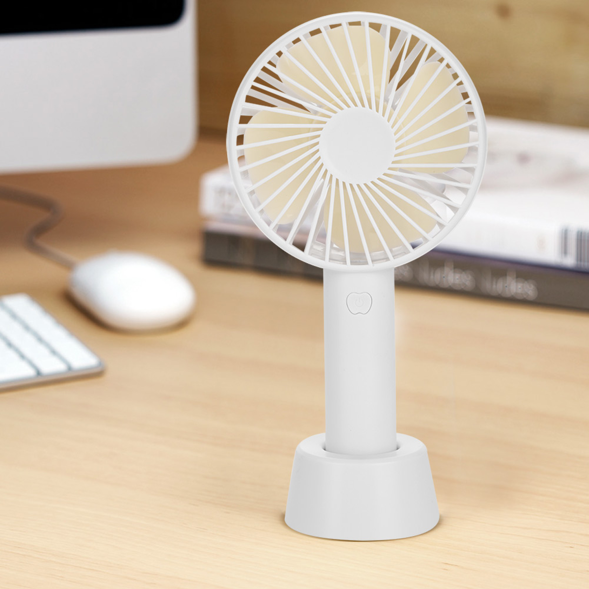Ein kleiner weißer Ventilator steht auf einem Holzschreibtisch neben einer Tastatur und Maus.